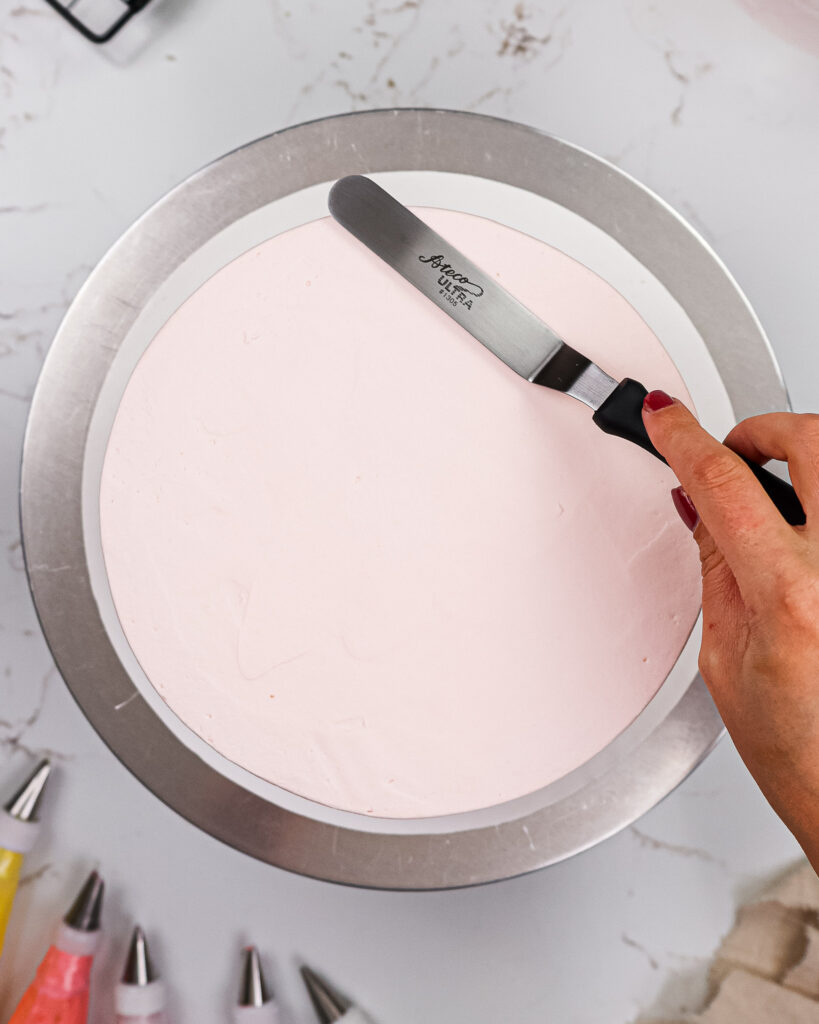 image of a cake that's being frosted with light pink buttercream