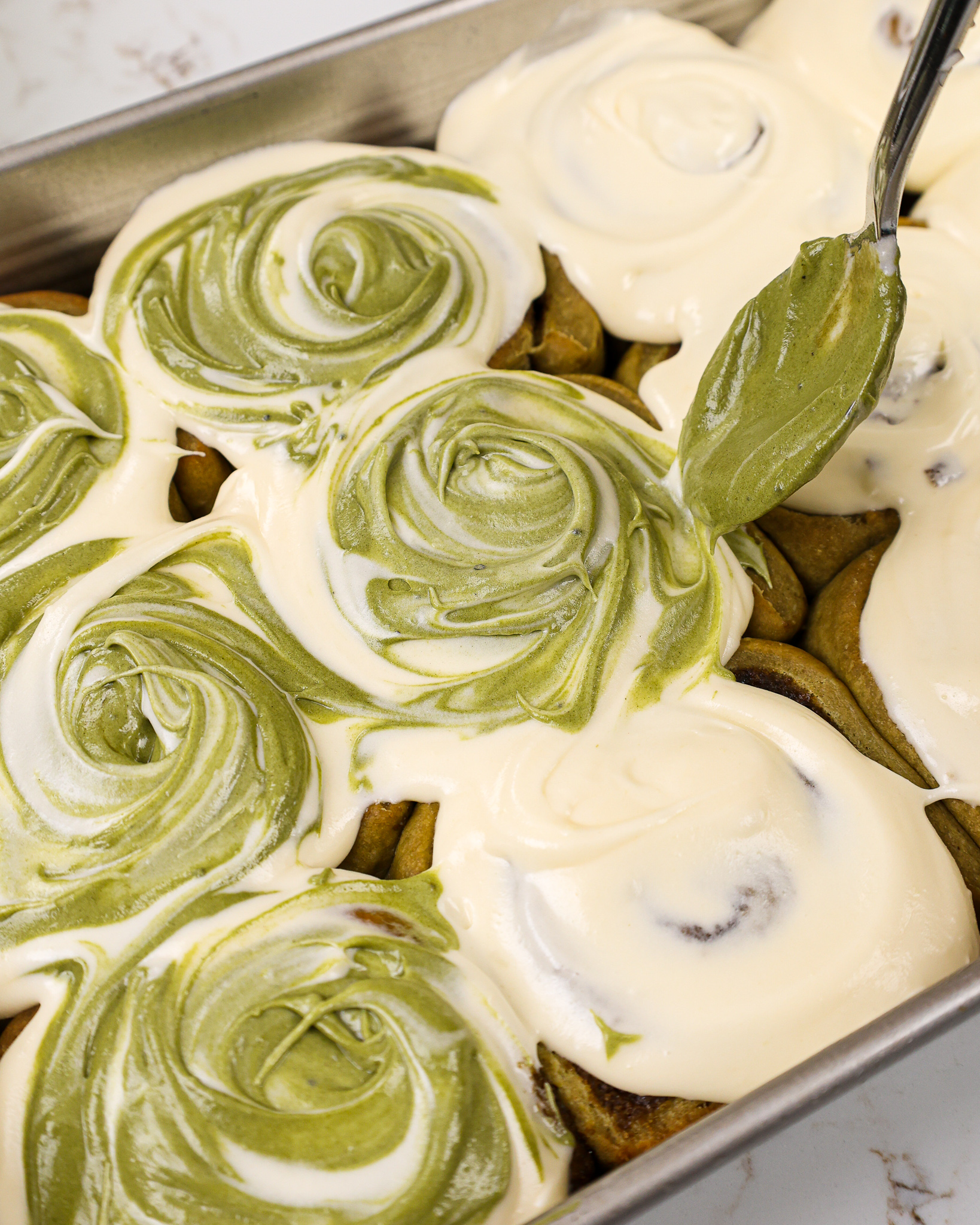 image of pretty matcha cinnamon rolls that have been topped with cream cheese and matcha frosting that has been swirled together