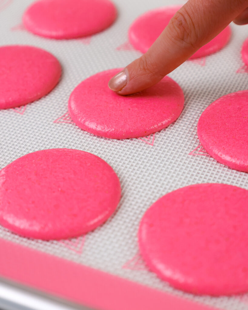 image of a pink macaron shell that's been rested and formed a skin and look matte and is ready to be baked