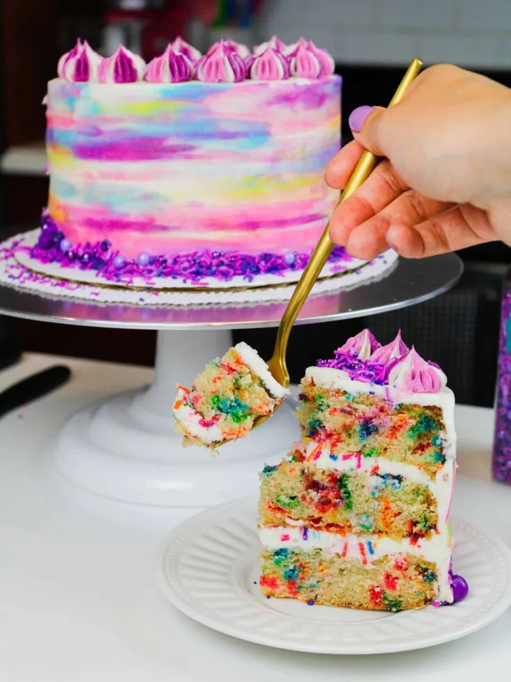 image of vegan funfetti cake with slice on plate and bite about to be taken with a fork
