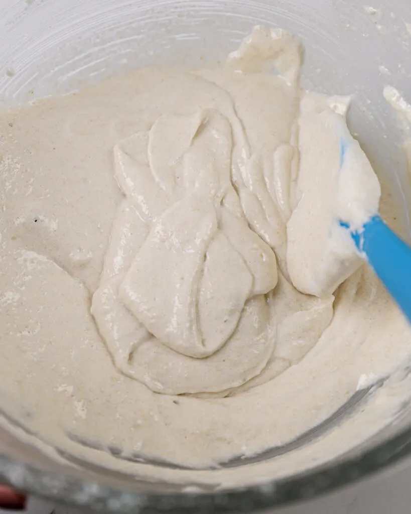 image of white macaron batter that's been mixed properly and can be used to draw a figure 8 with the thick stream of batter that runs off the spatula when it is lifted