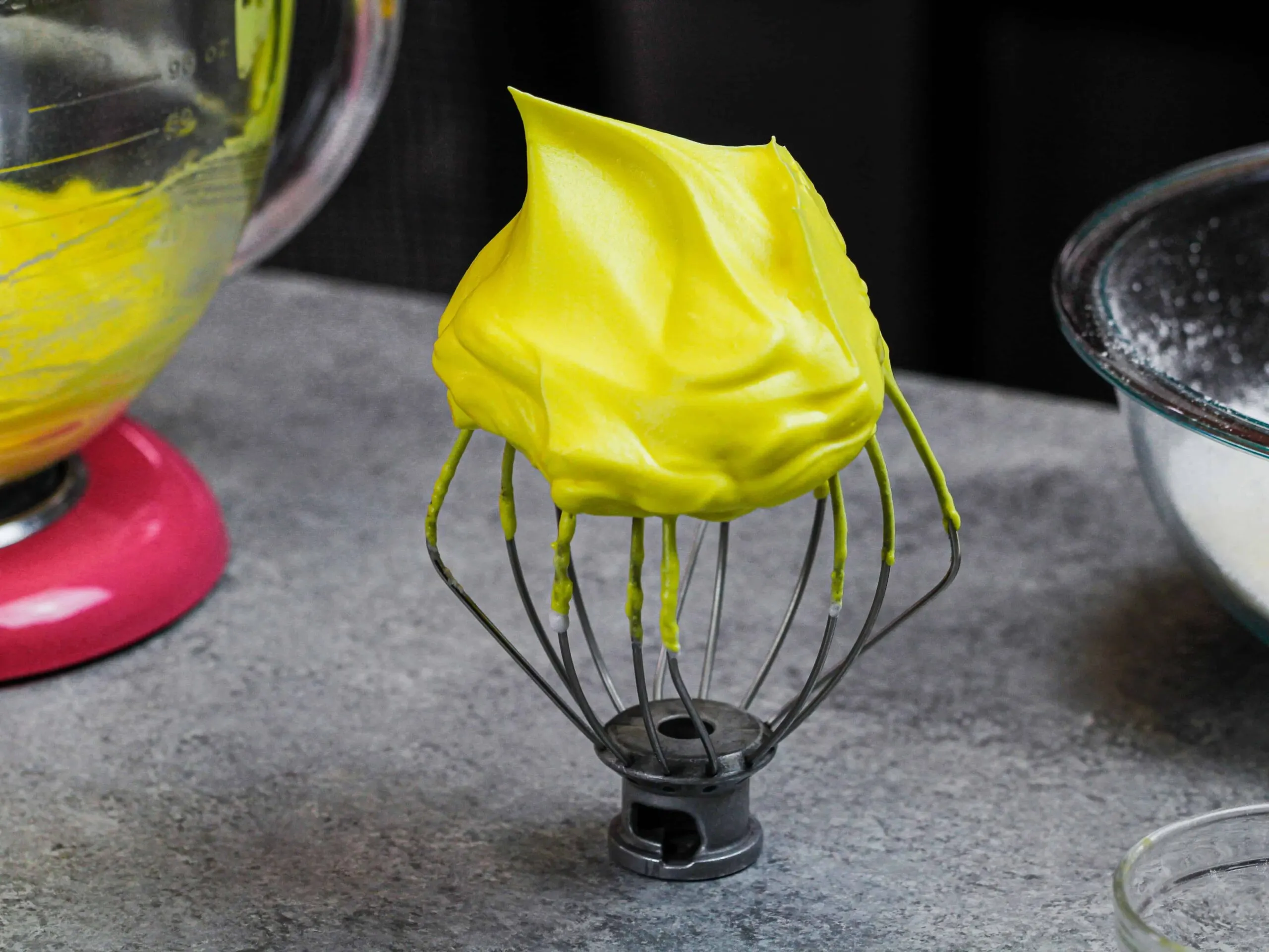 image of french meringue on a whisk that's been colored yellow with gel food coloring