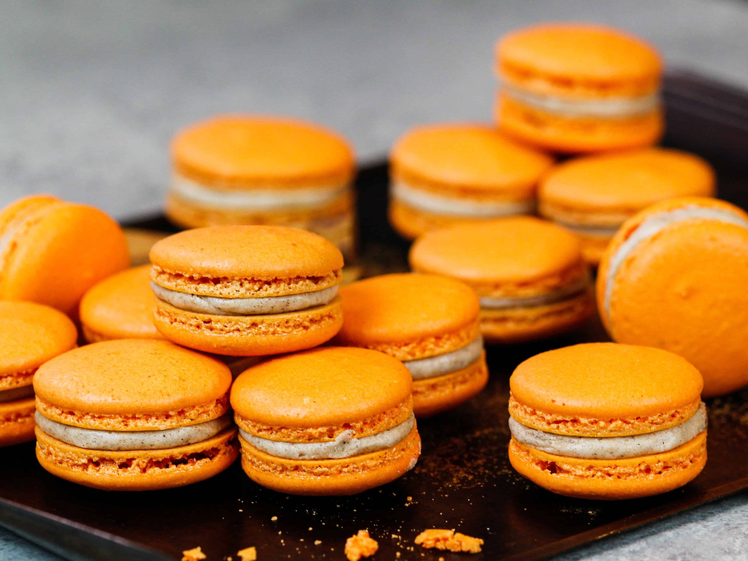 image of pumpkin macarons filled and resting on a tray before being eaten
