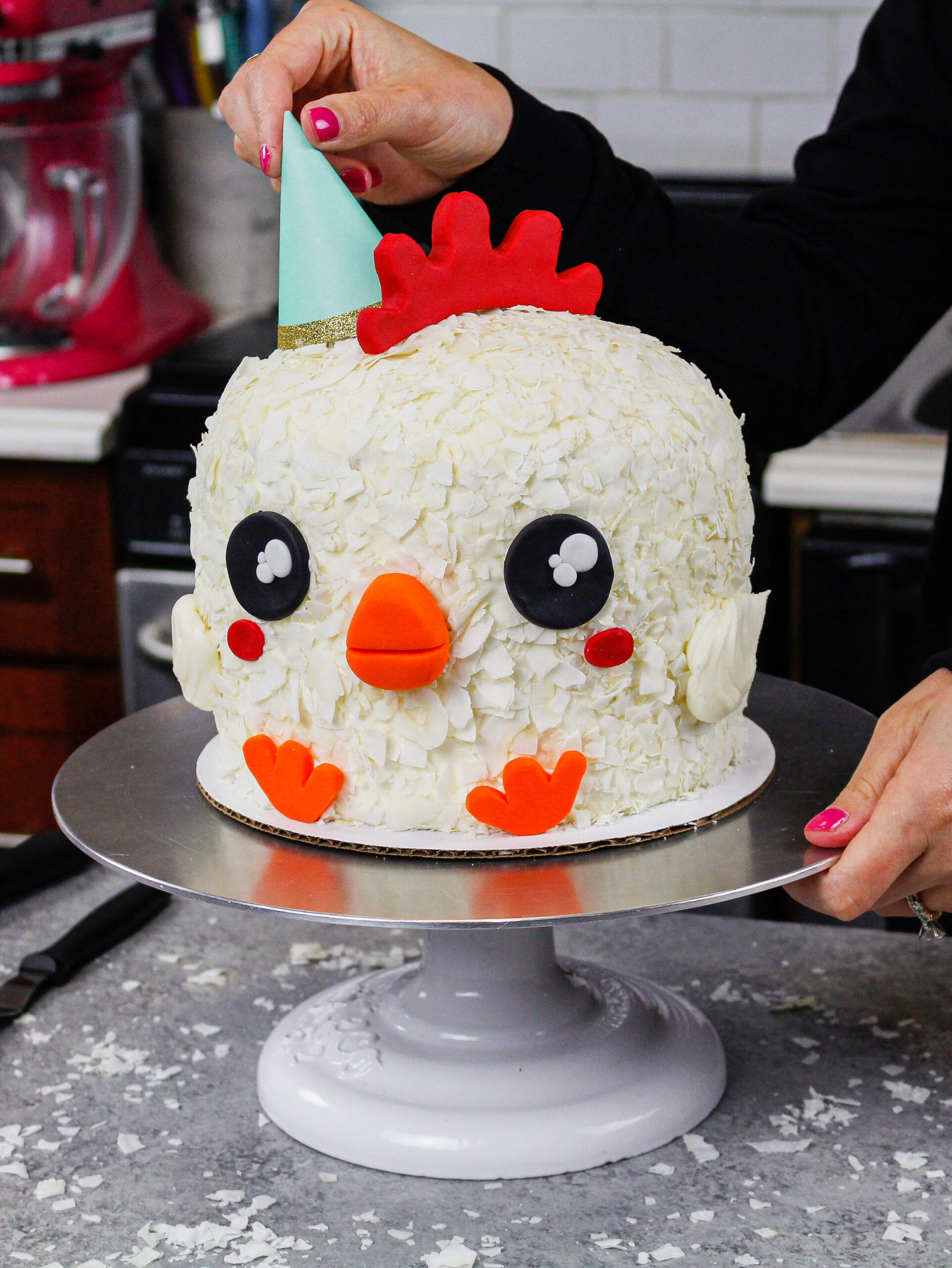 image of chelsey white placing a party hat on a spring chicken cake as part of her animal face series