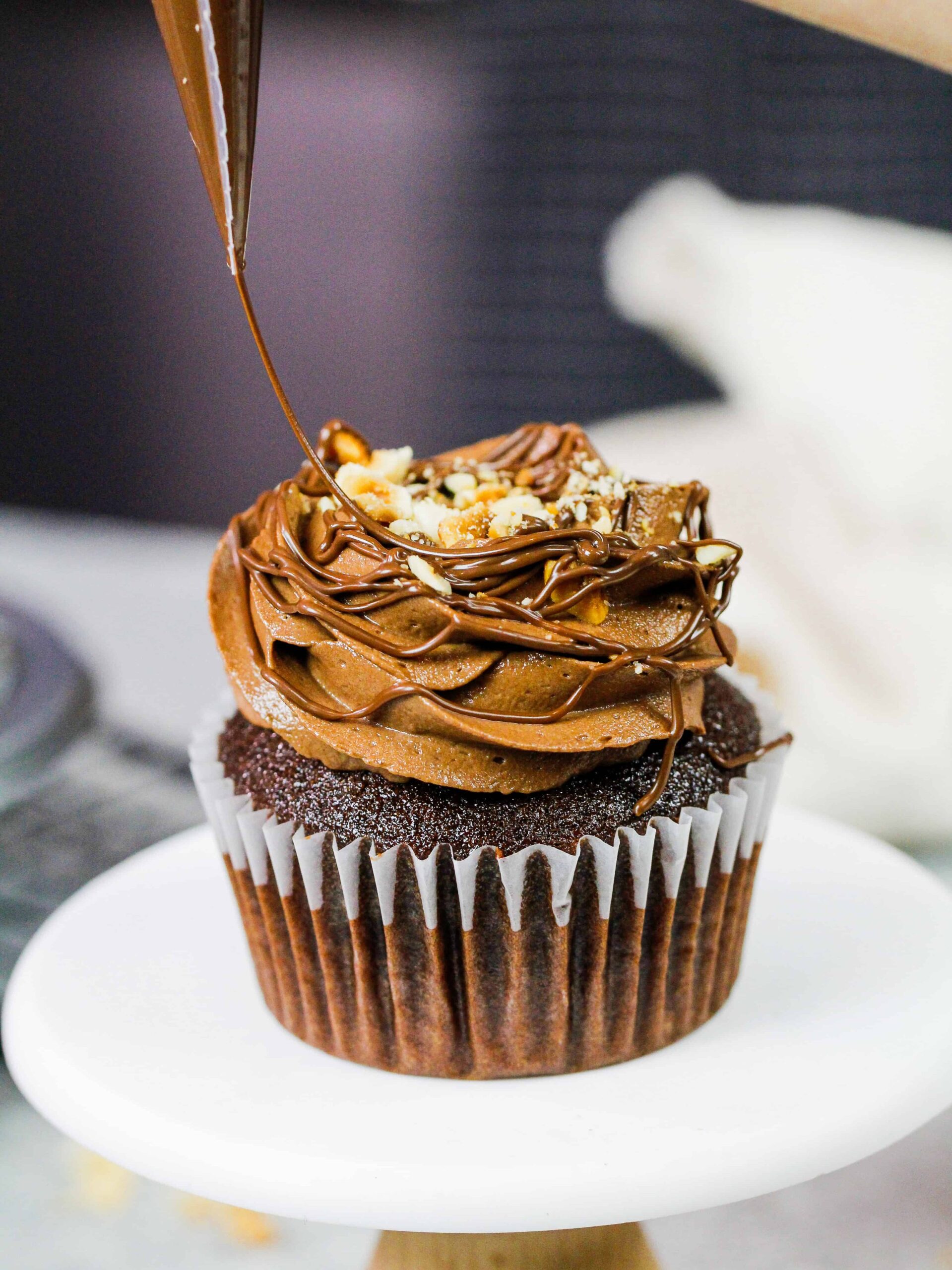 image of a Nutella cupcake being drizzled with additional Nutella to decorate it