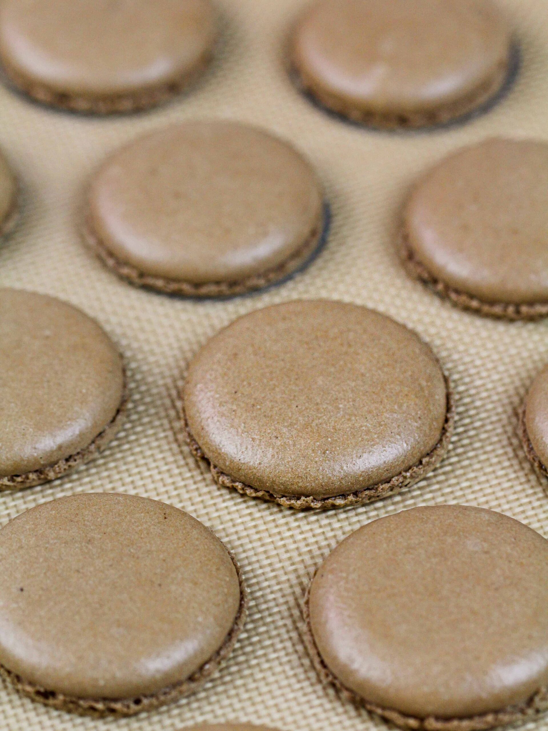 image of chocolate macaron shells baked on a silpat mat and cooling
