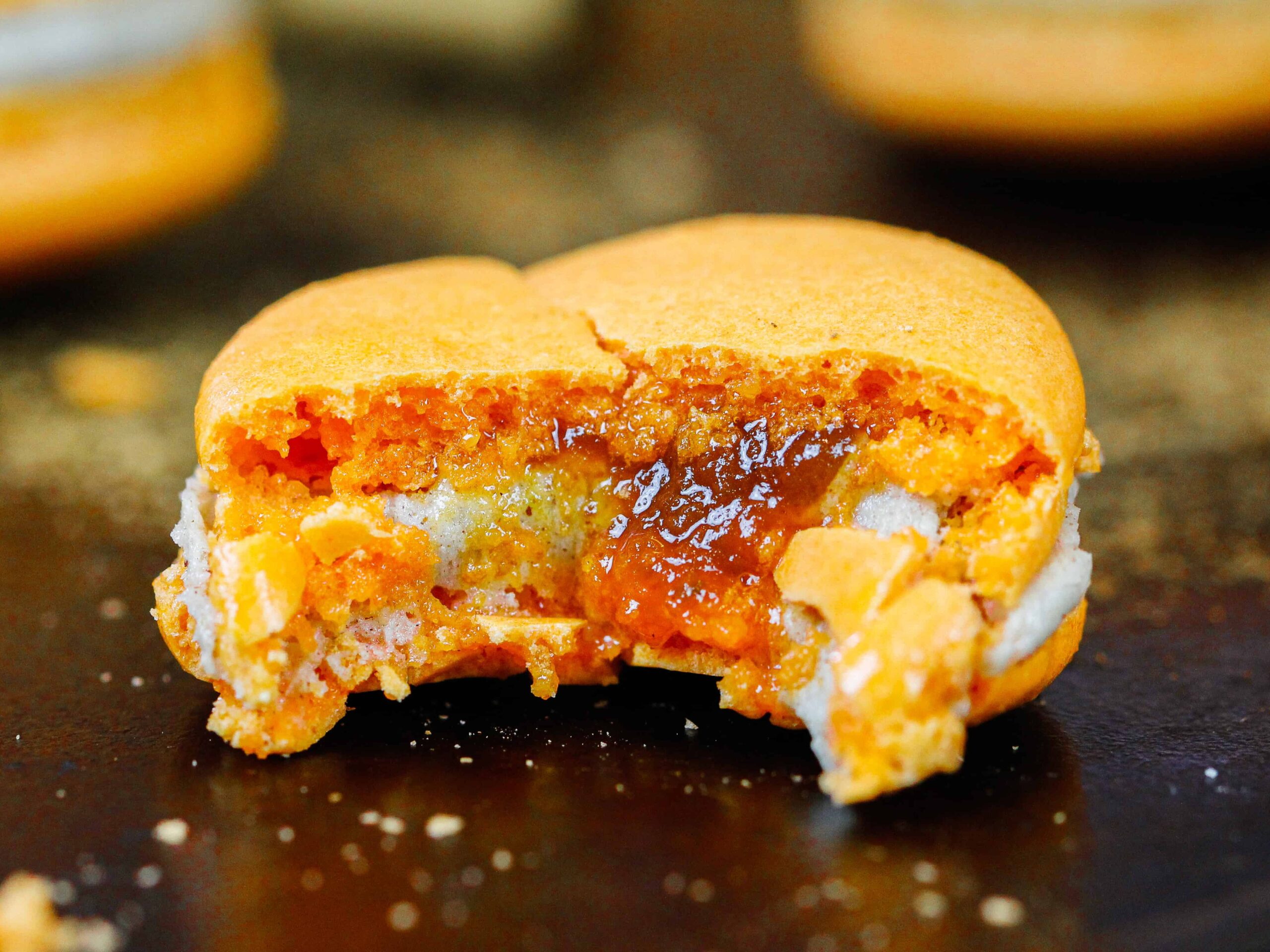 image of a pumpkin macaron being filled with spiced buttercream and pumpkin pie filling