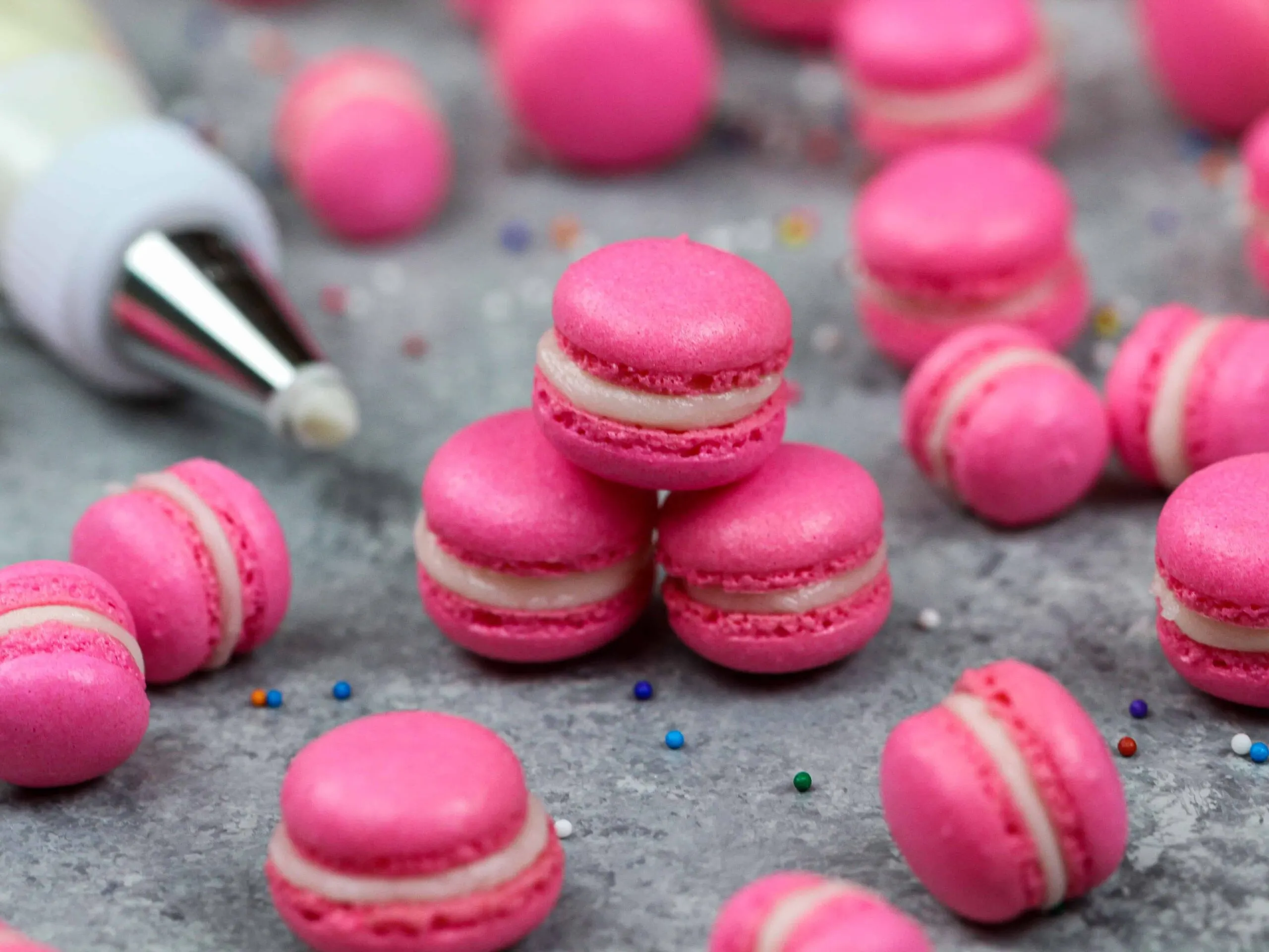 image of mini macarons colored pink with gel food coloring and filled with american buttercream