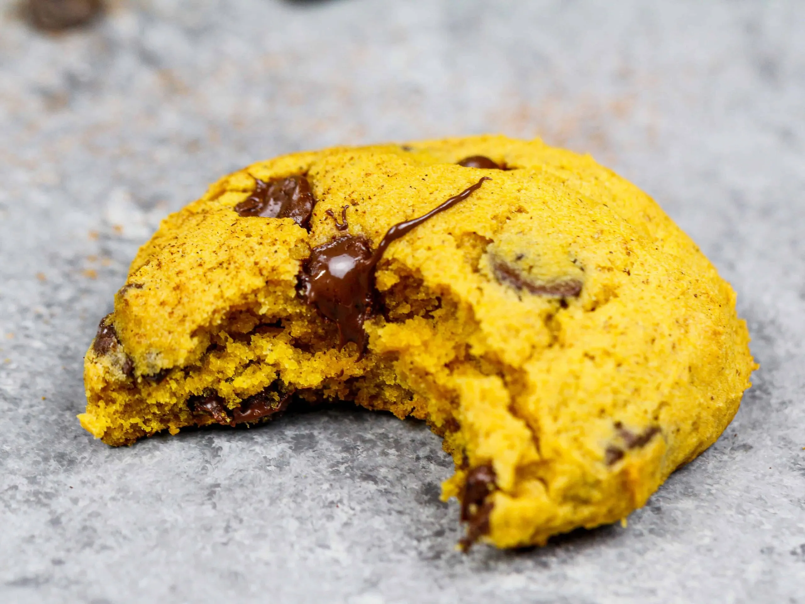 image of a bitten into vegan chocolate chip pumpkin cookie to show it's light and fluffy texture