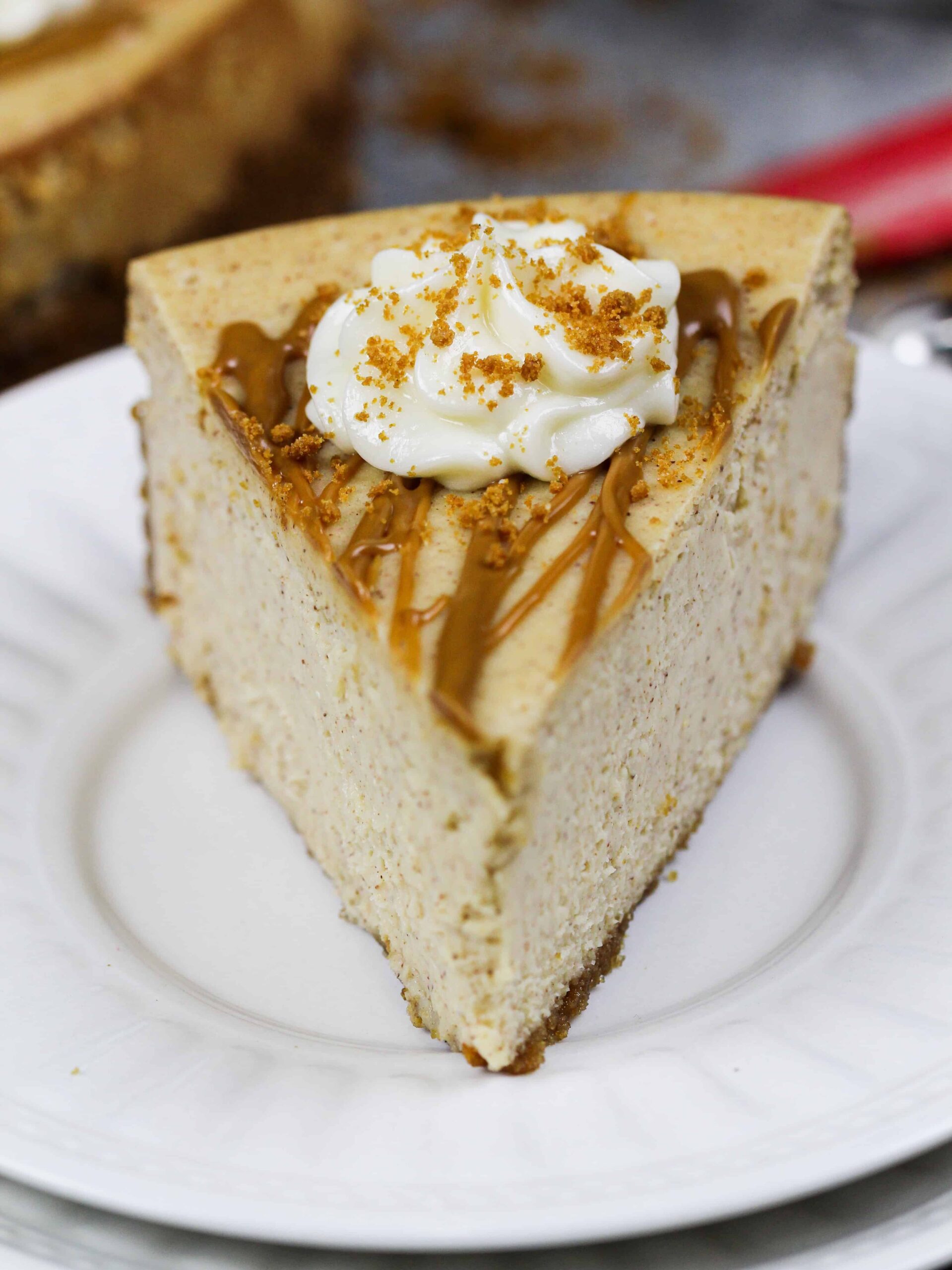 image of a slice of biscoff cheesecake drizzled with cookie butter and topped with whipped cream