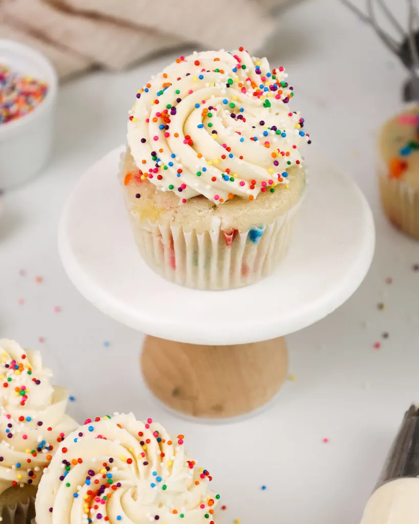 image of sprinkles being added to a cupcake frosted with a perfectly sweet buttercream