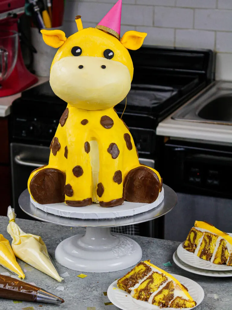 image of a cute giraffe birthday cake that's been cut into to show its yellow marble cake layers