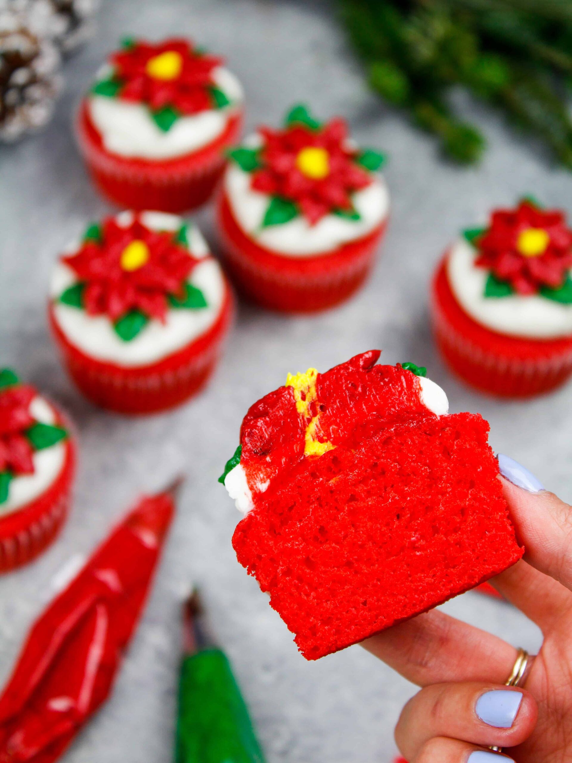 image of a red cupcake that's been decorated with a frosting poinsettia and been cut into to show how moist and tender it is