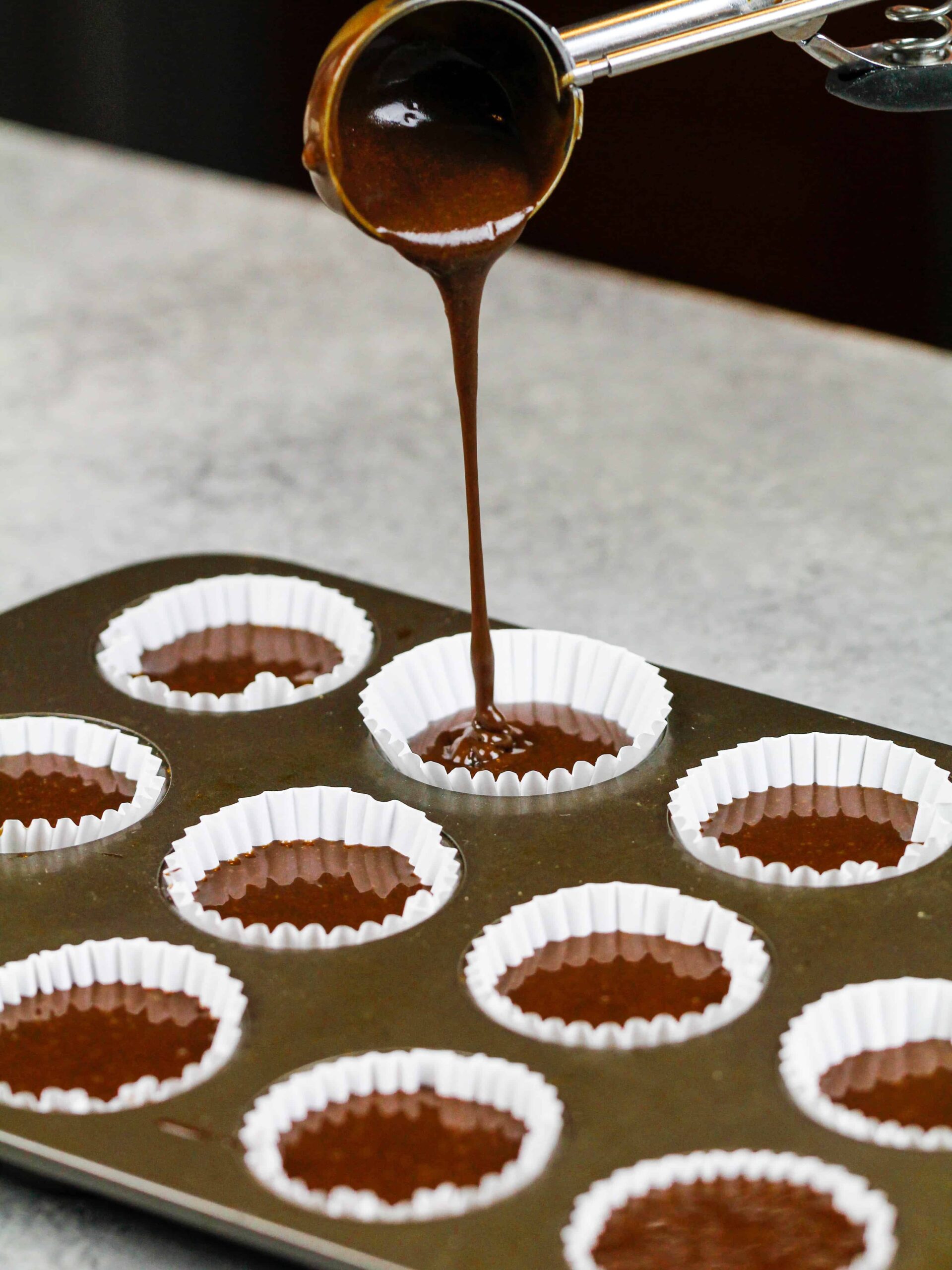 image of mini cupcake liners being filled with chocolate cupcake batter
