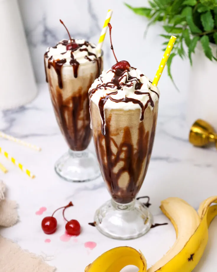 image of a dirty monkey drink that's been made with rum and bananas and has been poured into a chocolate syrup lined milkshake glass