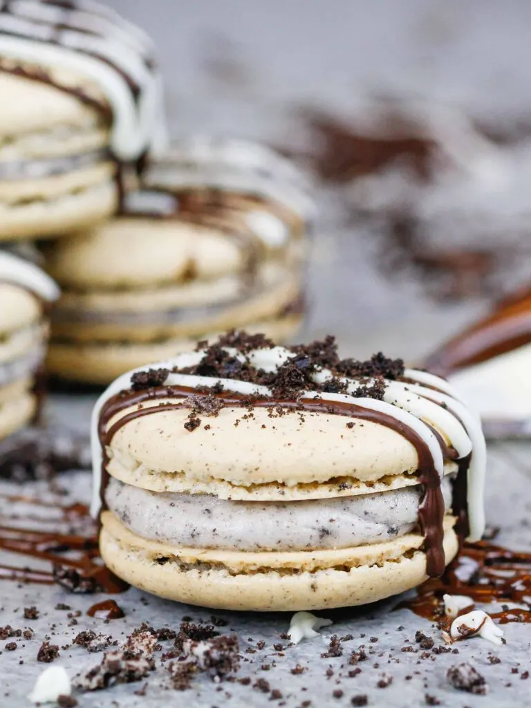 image of oreo macarons decorated with a chocolate drizzle and oreo crumble