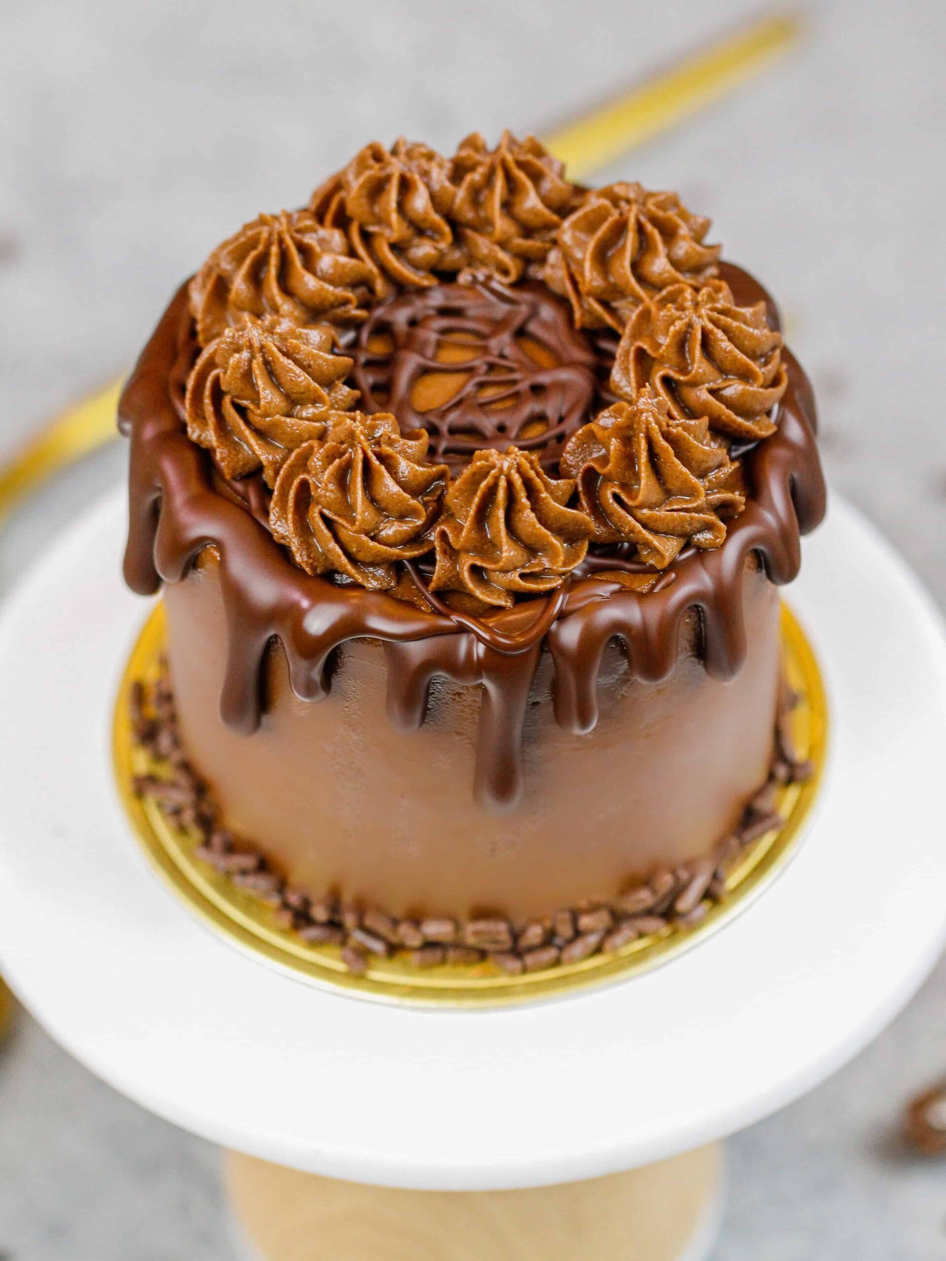 image of a mini chocolate cake decorated with a chocolate drip and chocolate sprinkles
