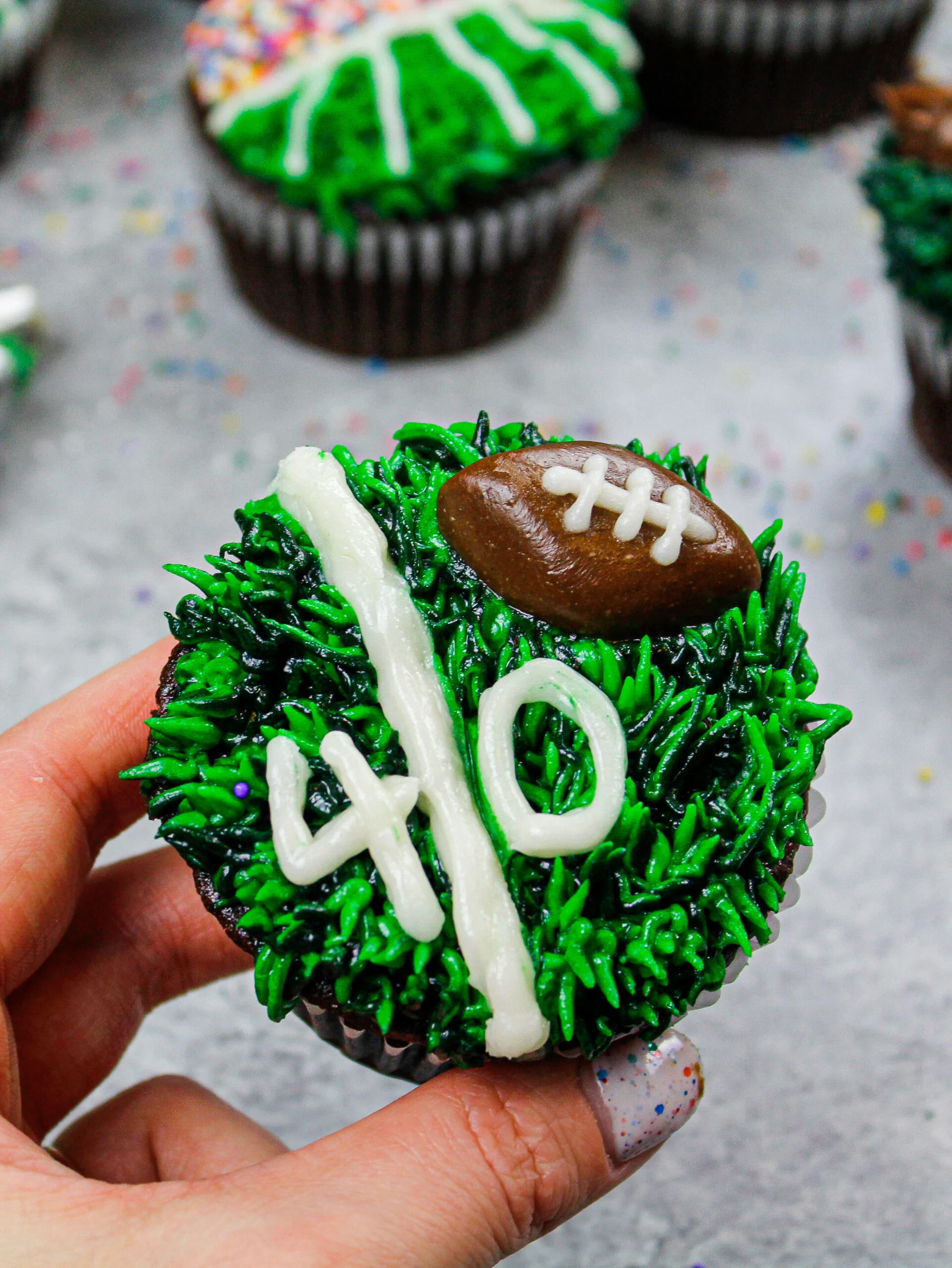 image of a football cupcake decorated to look like a yard line with a tootsie roll football
