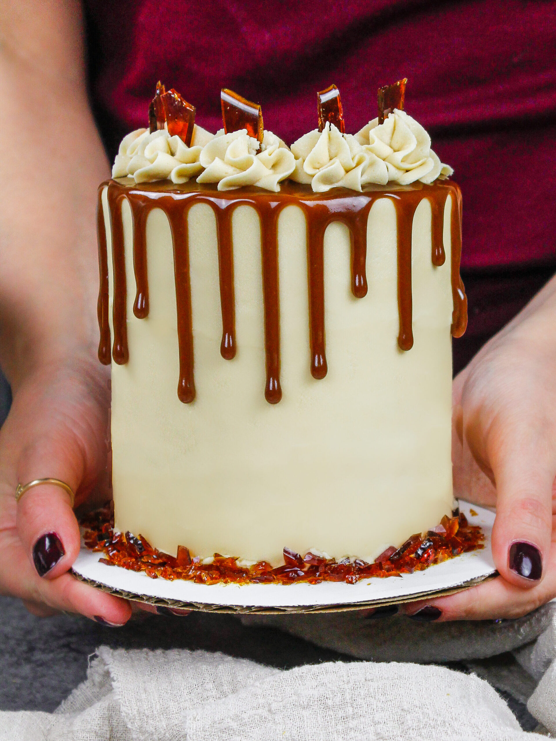 image of an adorable caramel brown sugar drip cake being held to show how small this 4-inch cake is