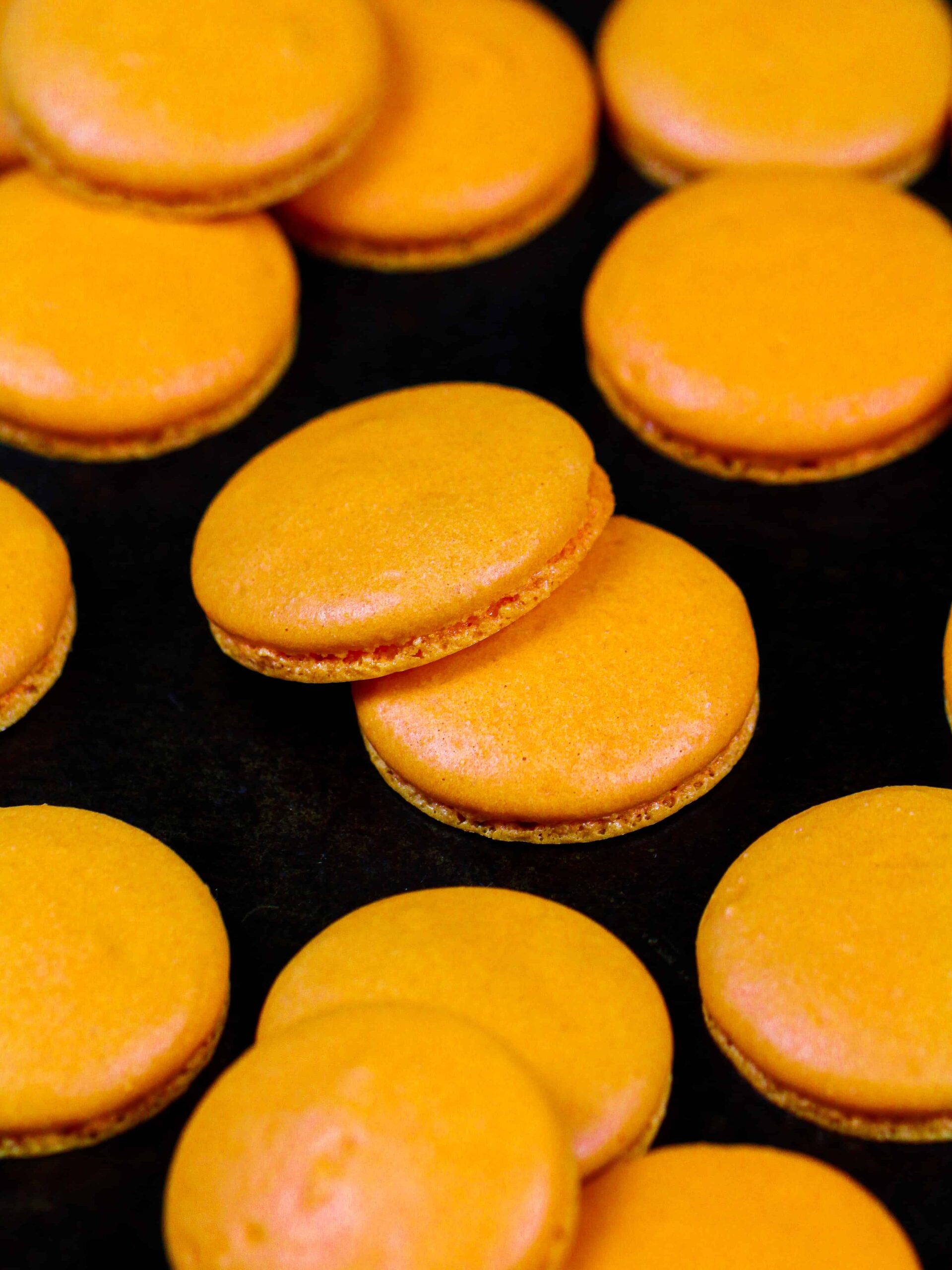 image of orange macaron shells that have been baked to make pumpkin macarons