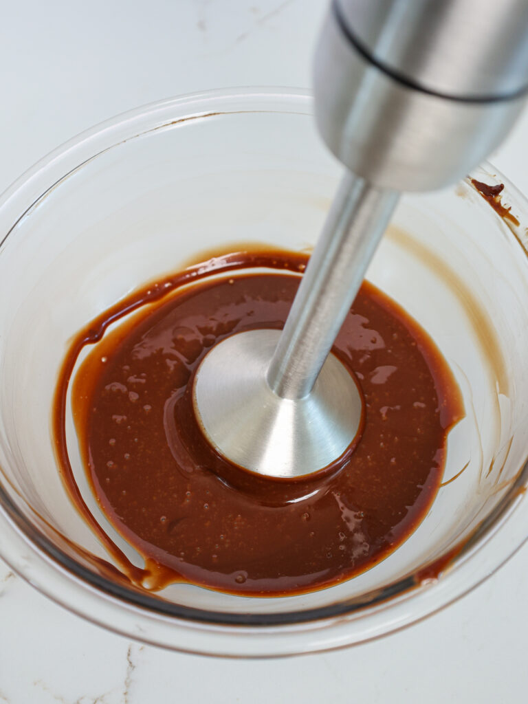 image of chocolate ganache filling for macarons that's being mixed with an immersion blender to make it super smooth