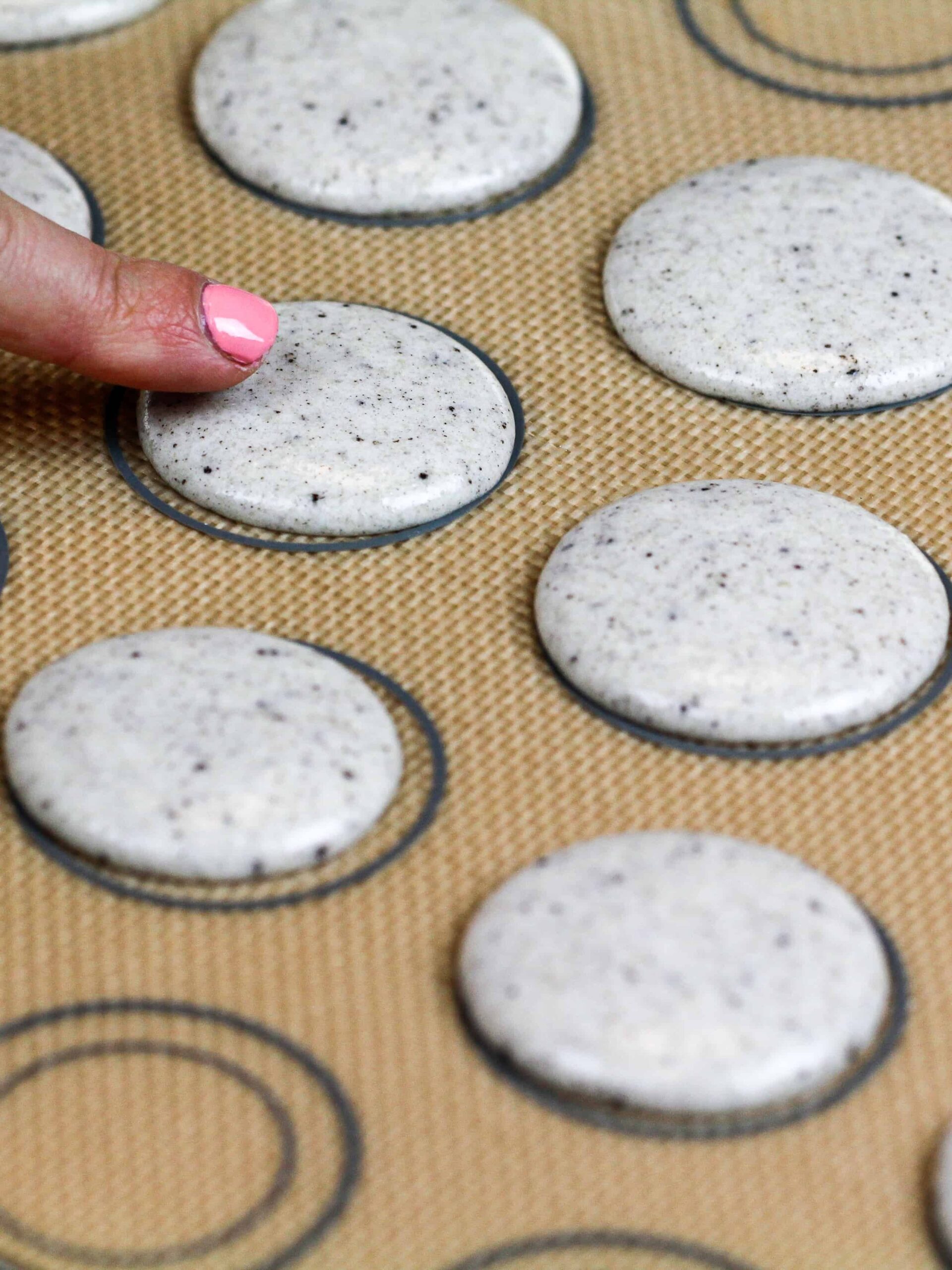 image of macaron shells piped onto a silpat mat and rested to form a skin before being baked