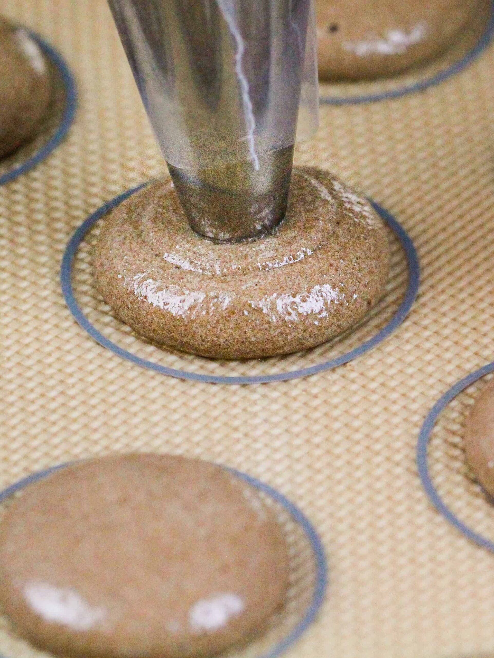 image of chocolate macarons being piped onto a silpat mat