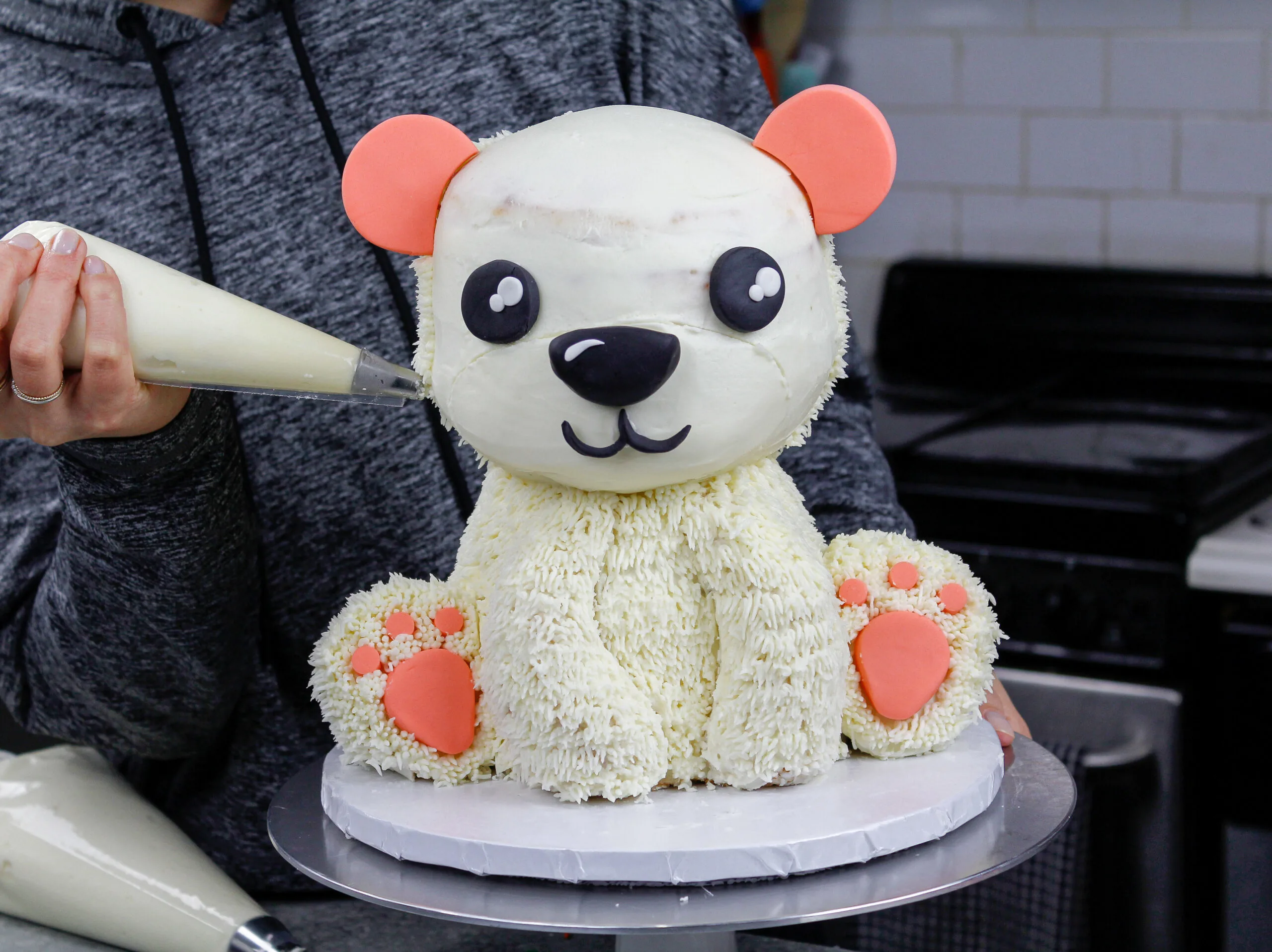 image of polar bear cake being covered in buttercream fur using a small grass tip