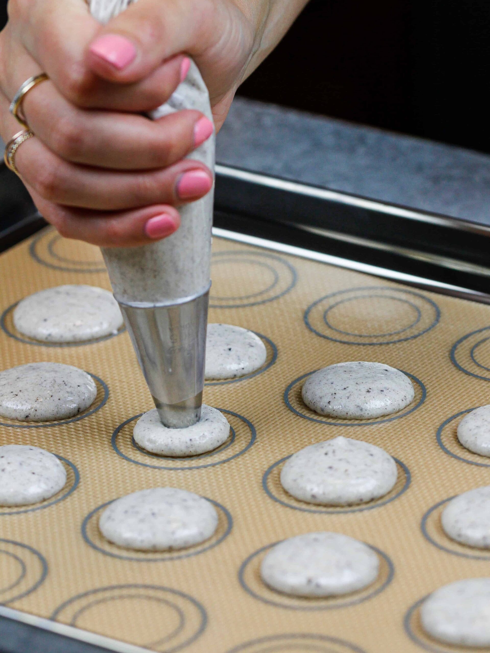 image of french cookies and cream macarons being piped onto a silpat mat
