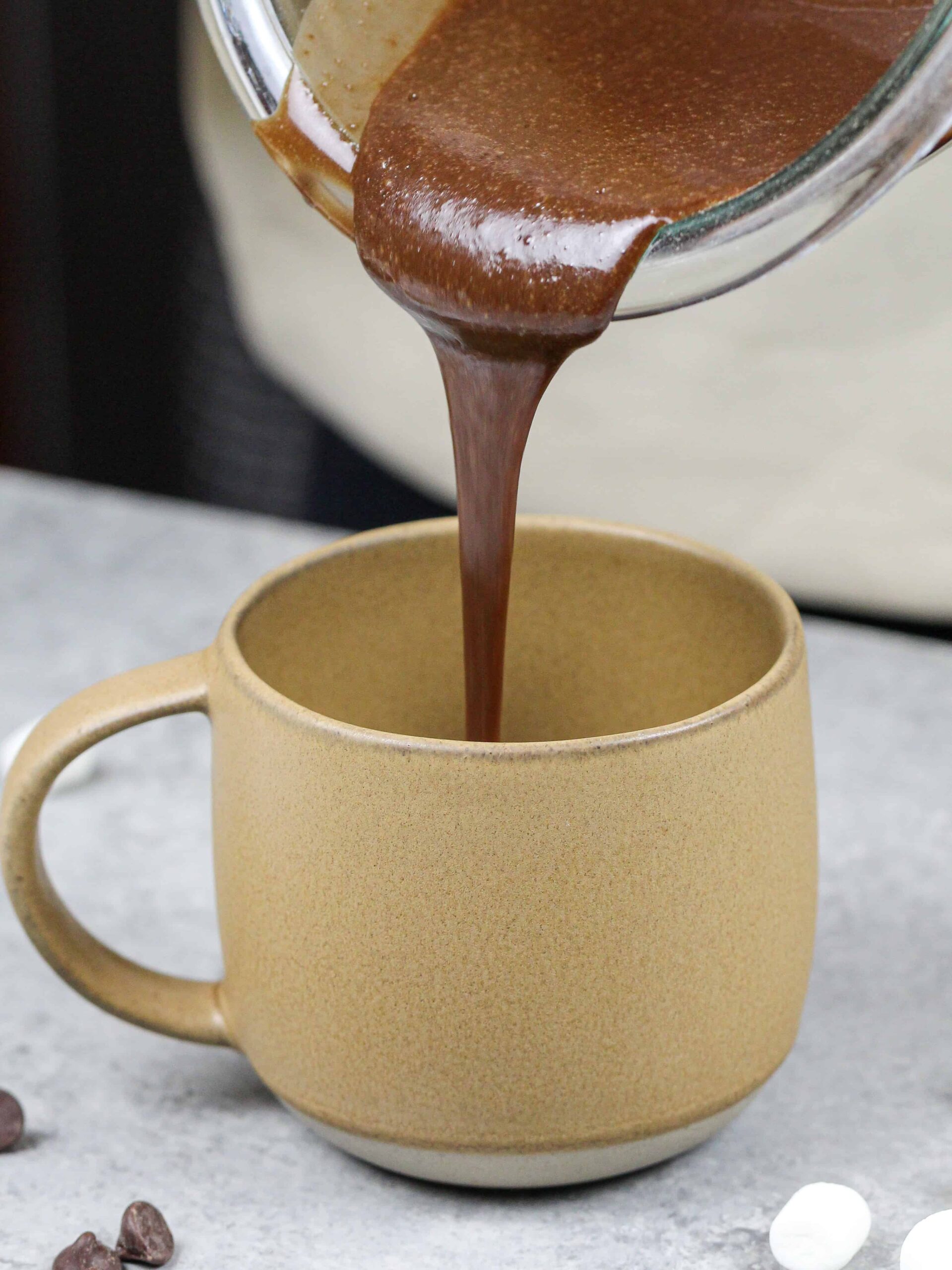 image of chocolate cake batter being poured into a mug to make a hot cocoa mug cake in the microwave