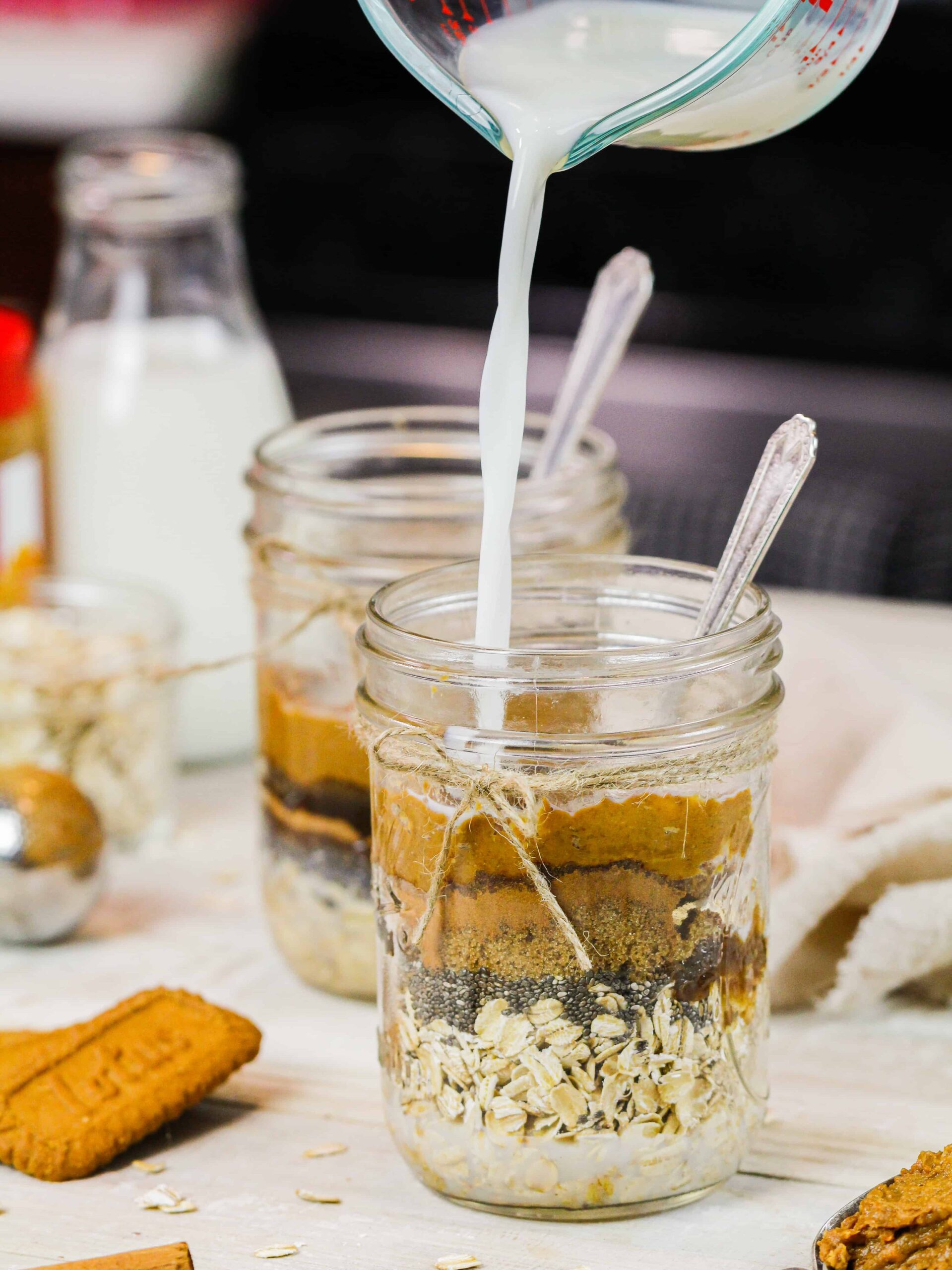 image of milk being poured into jar of biscoff overnight oats