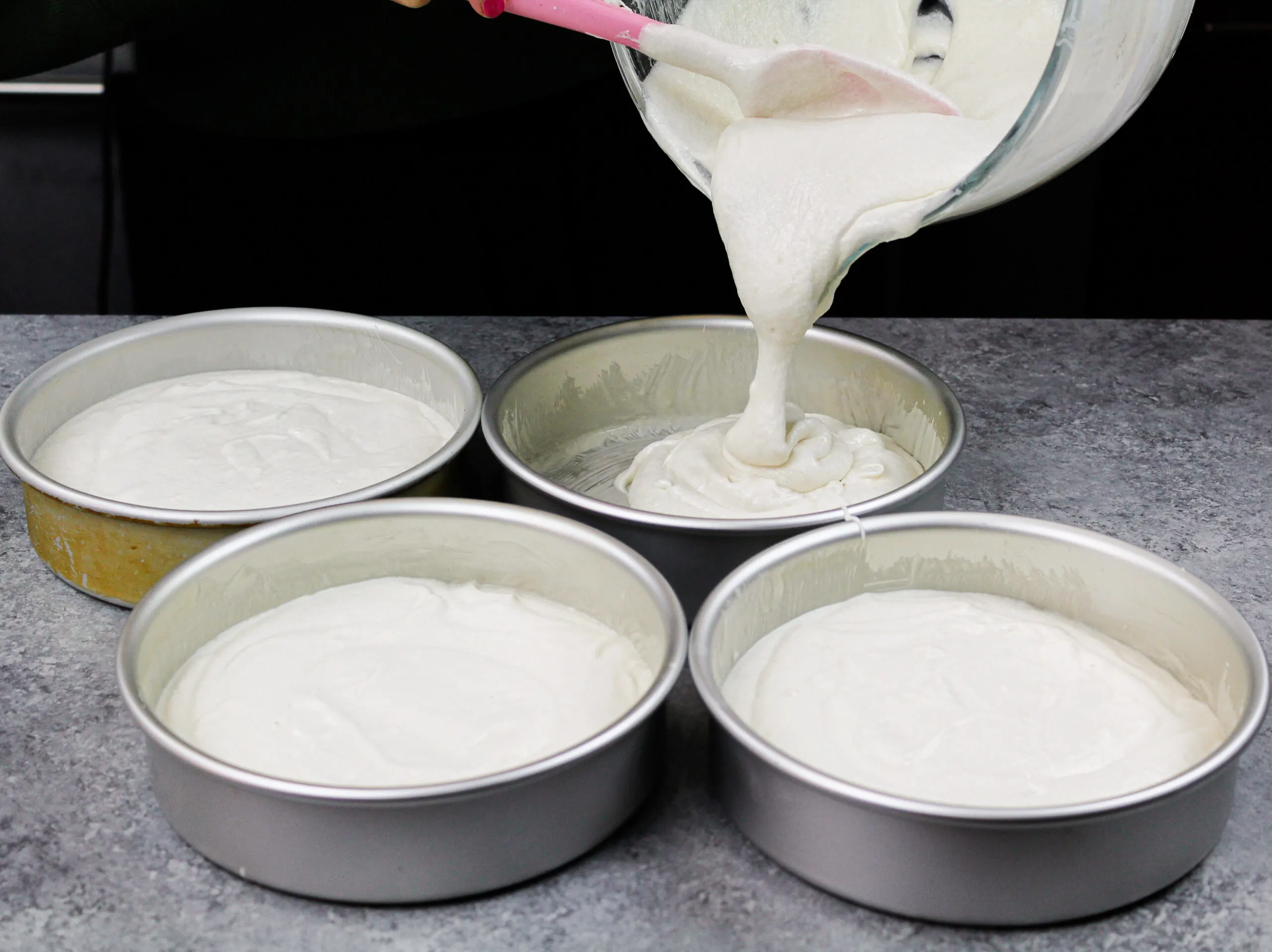 image of fluffy coconut cake batter being poured into pans to be baked