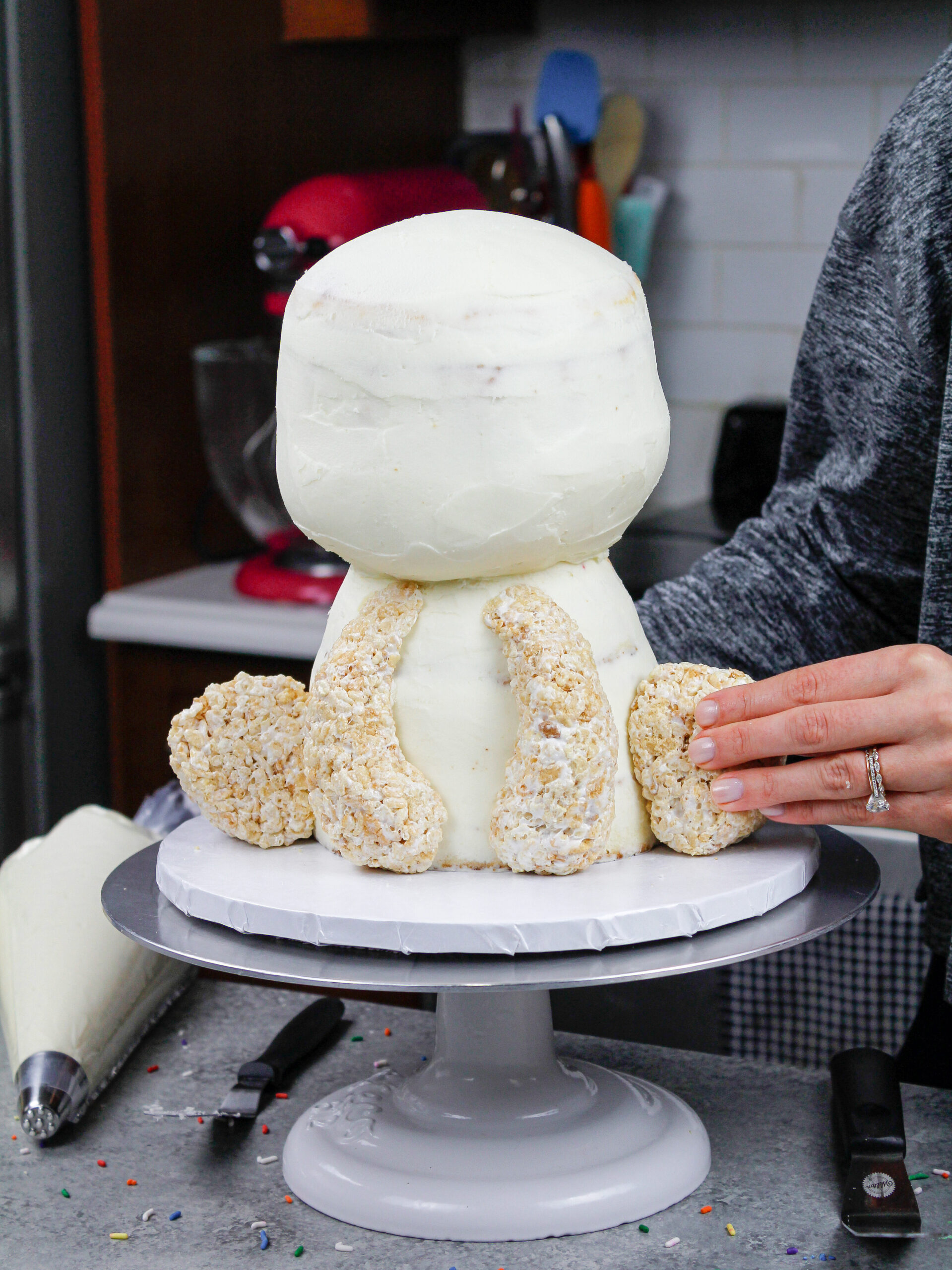 image of cake decorating rice krispie legs being added to a polar bear cake