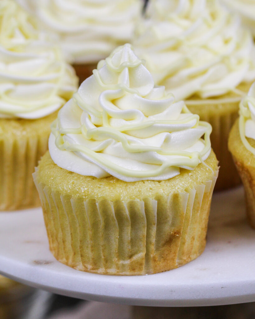 image of white chocolate cupcakes being topped with a drizzle of melted white chocolate