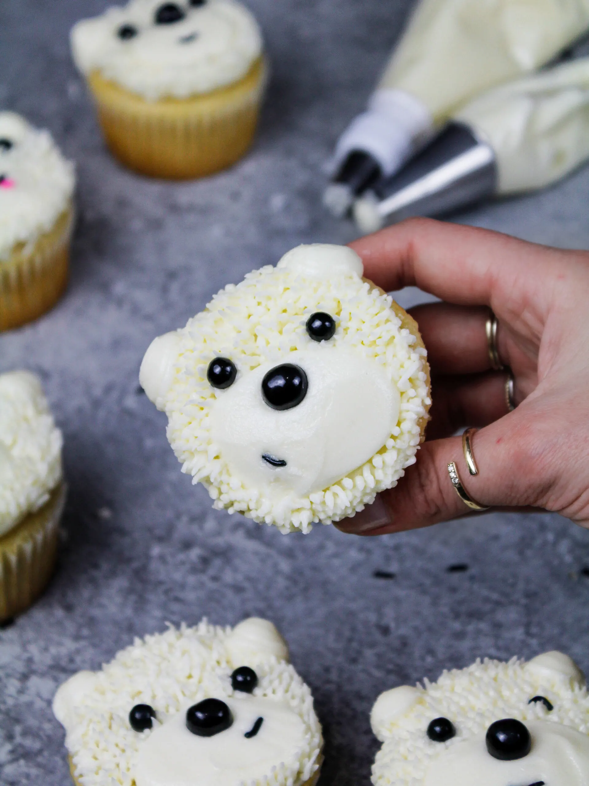 image of adorable polar bear cupcakes made with buttercream frosting and black sprinkles