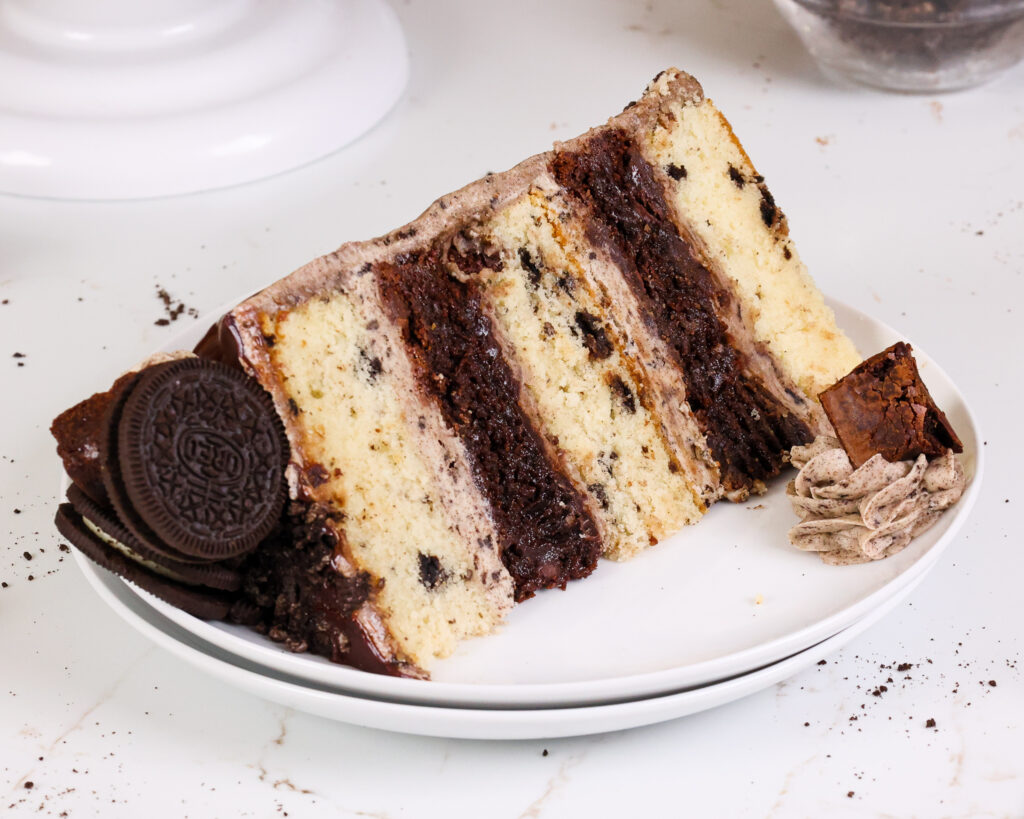 image of a brownie oreo cake that's been frosted with oreo buttercream and cut into to show it's alternating layers or oreo cake and brownie