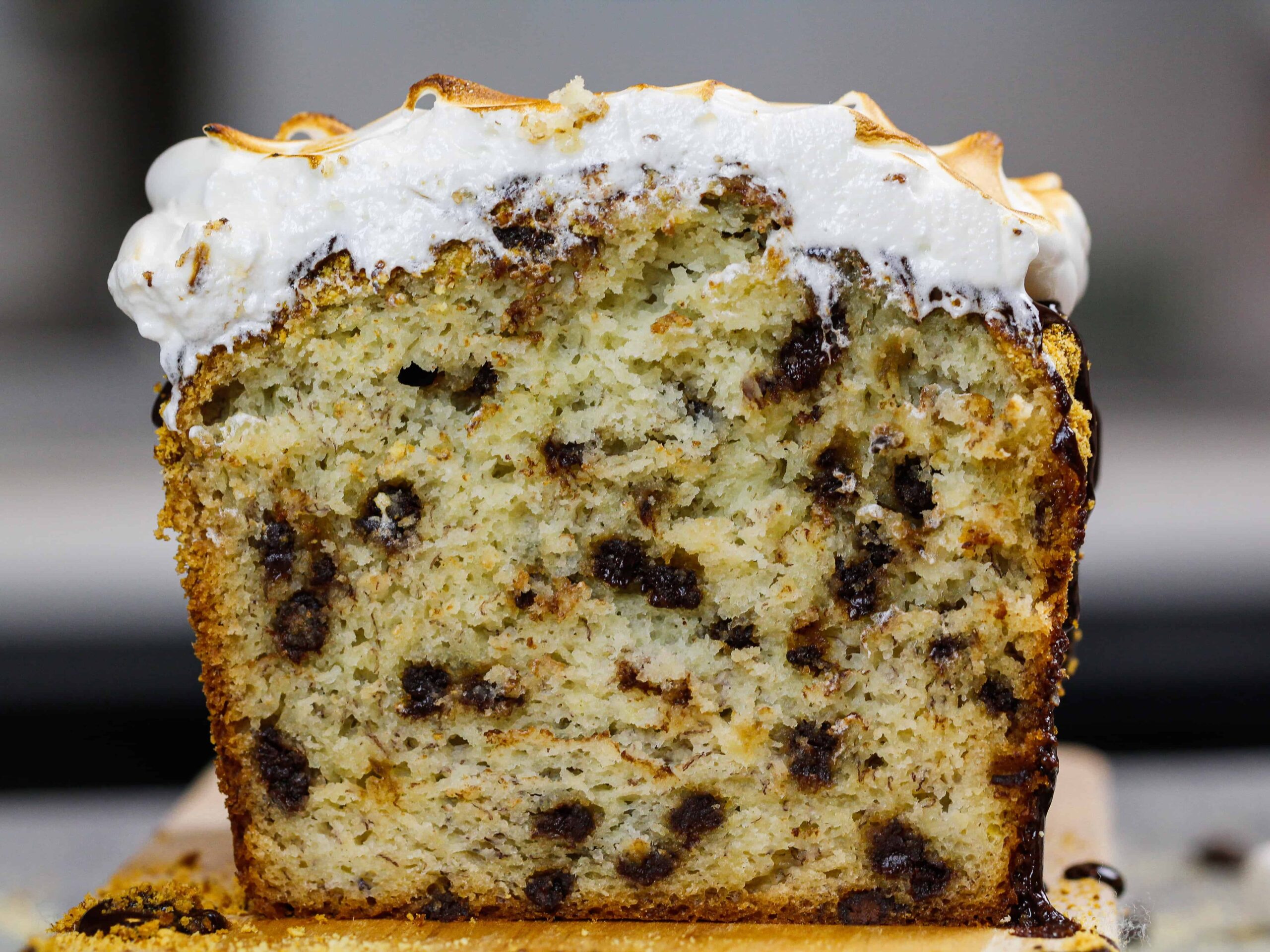 image of smores banana bread loaf cut open to show chocolate chips and toasted marshmallow topping