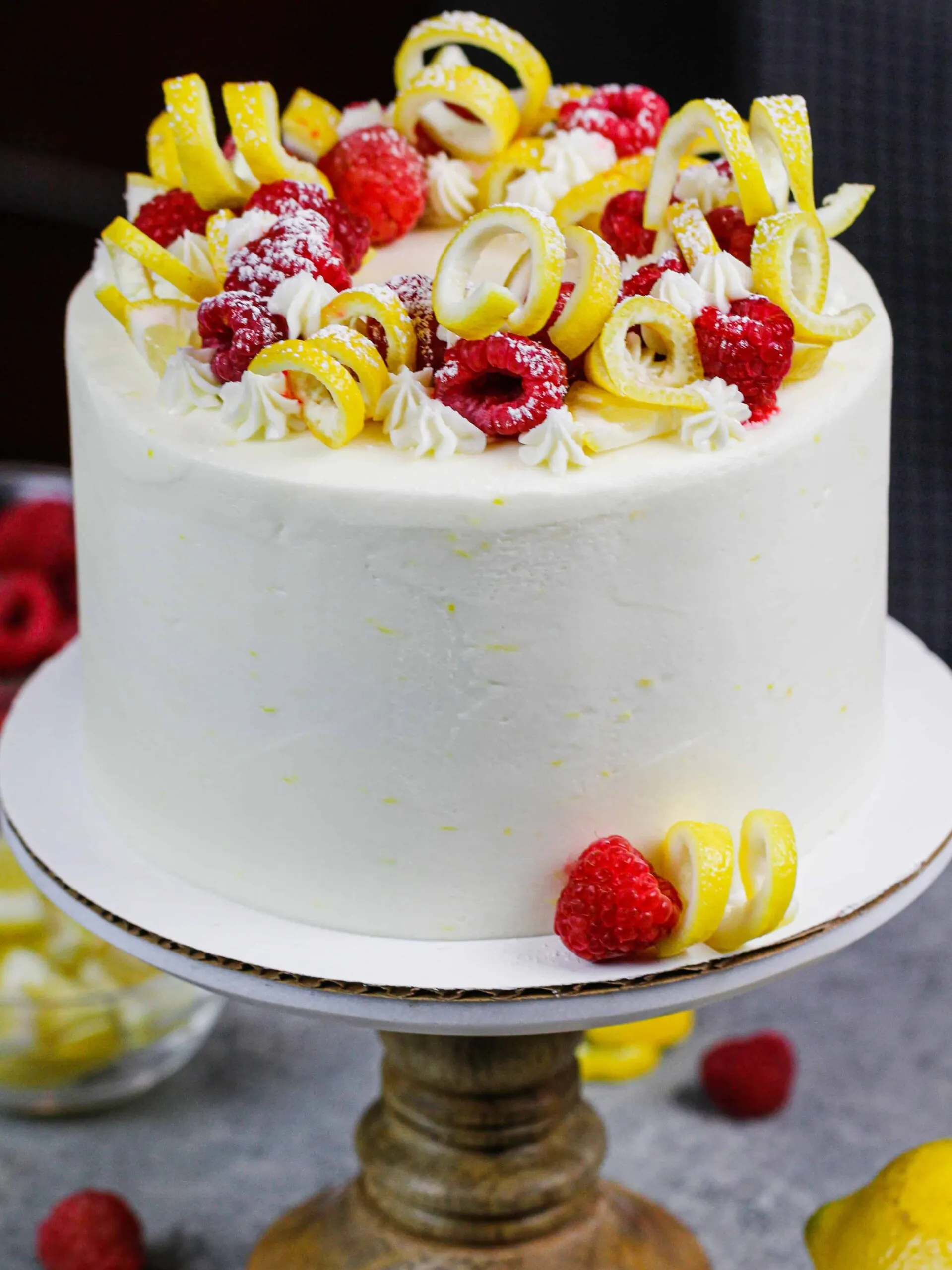 image of lemon raspberry cake decorated with lemon spirals and fresh raspberries