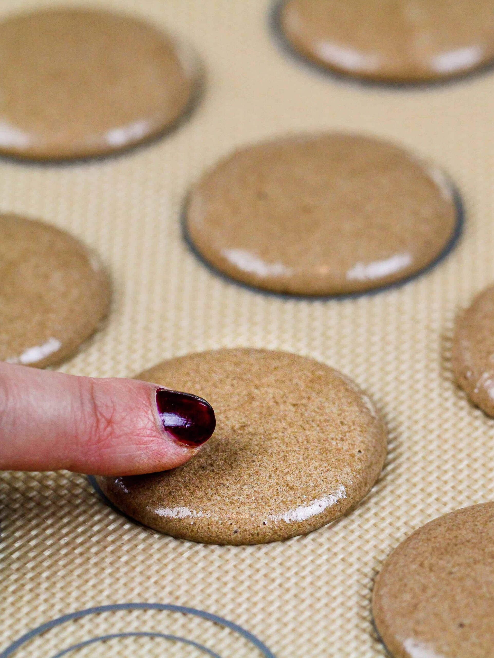 image of chocolate macarons piped on a silicon mat and resting to form a skin before being baked and made into Nutella macarons