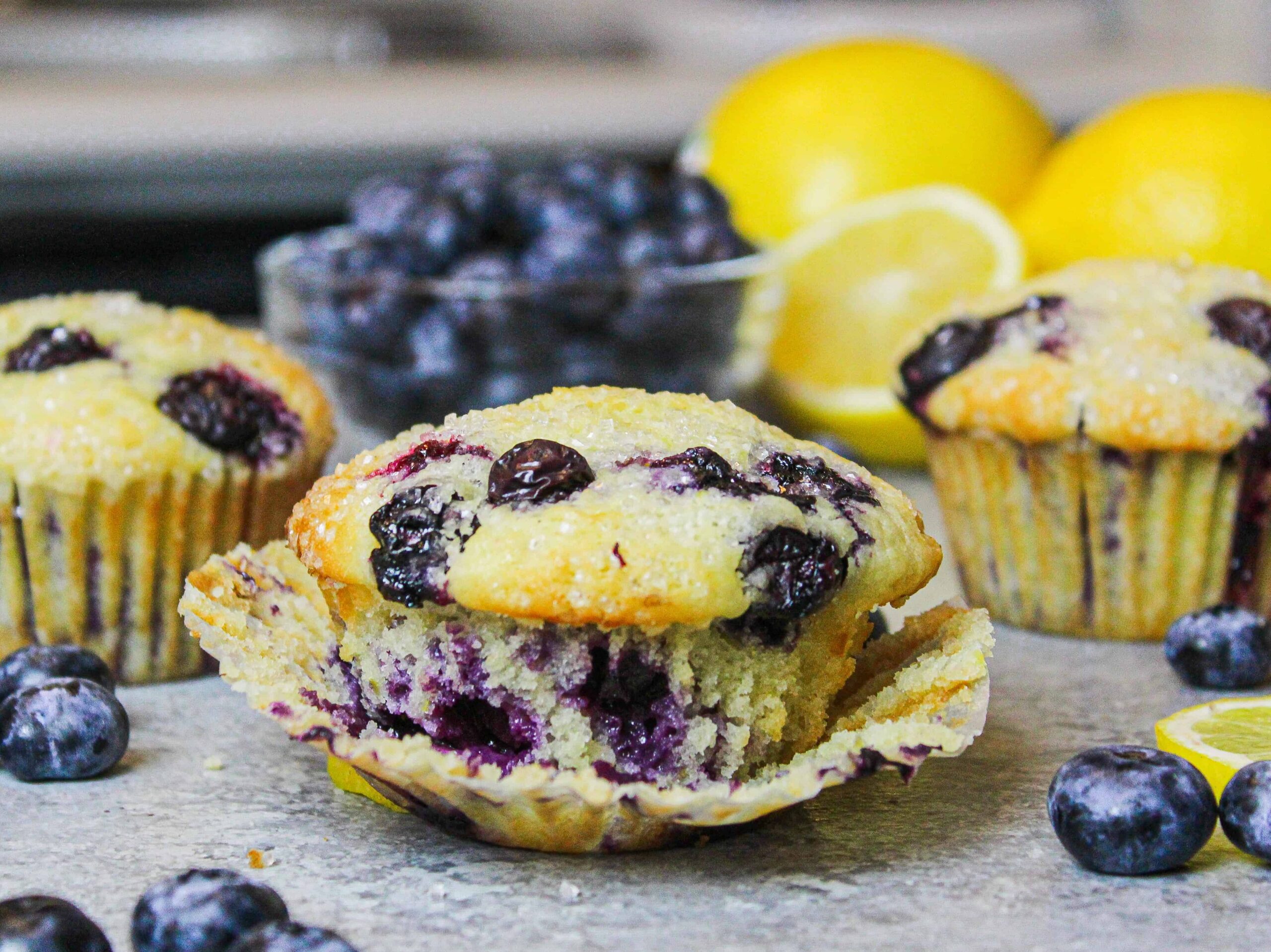 image of blueberry muffin surrounded by other muffins and fresh blueberries
