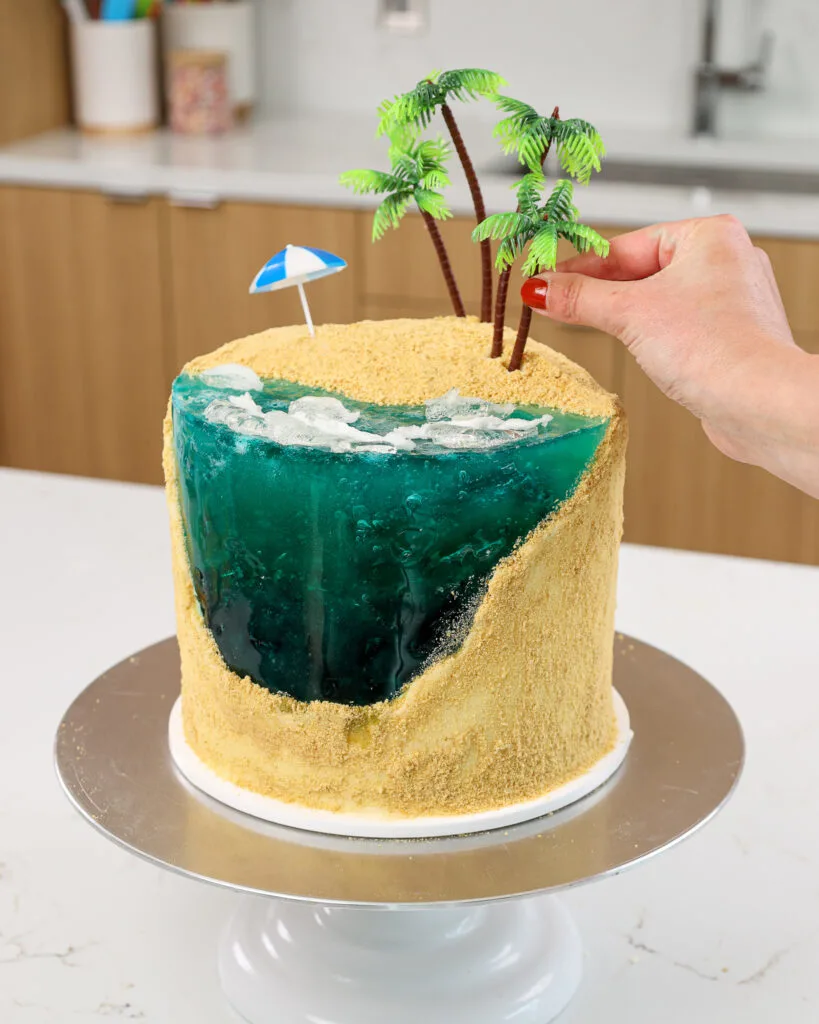 image of palm trees being pressed into place on a cute summer beach cake
