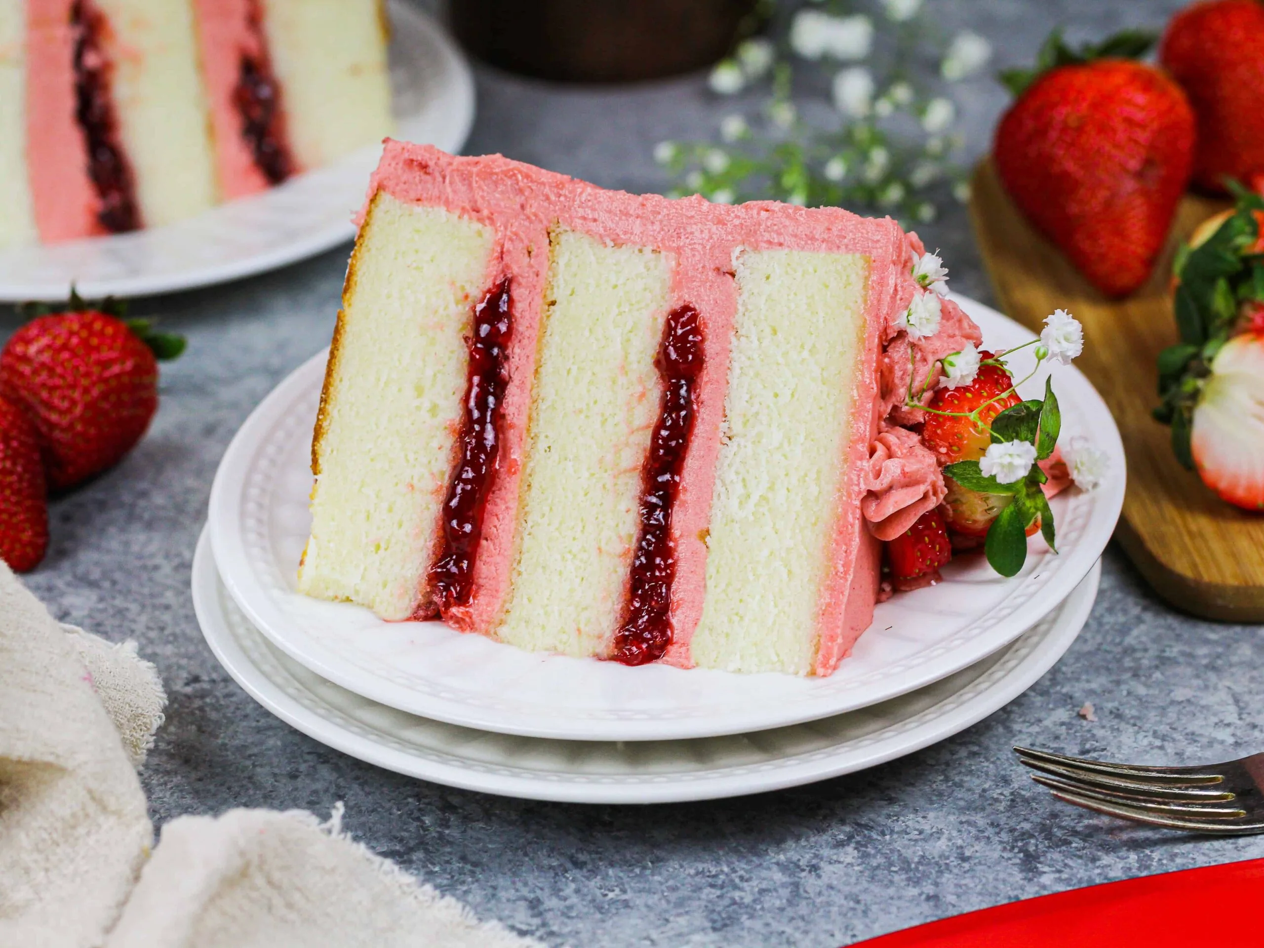 image of a slice of vanilla strawberry cake filled with strawberry jam and strawberry frosting