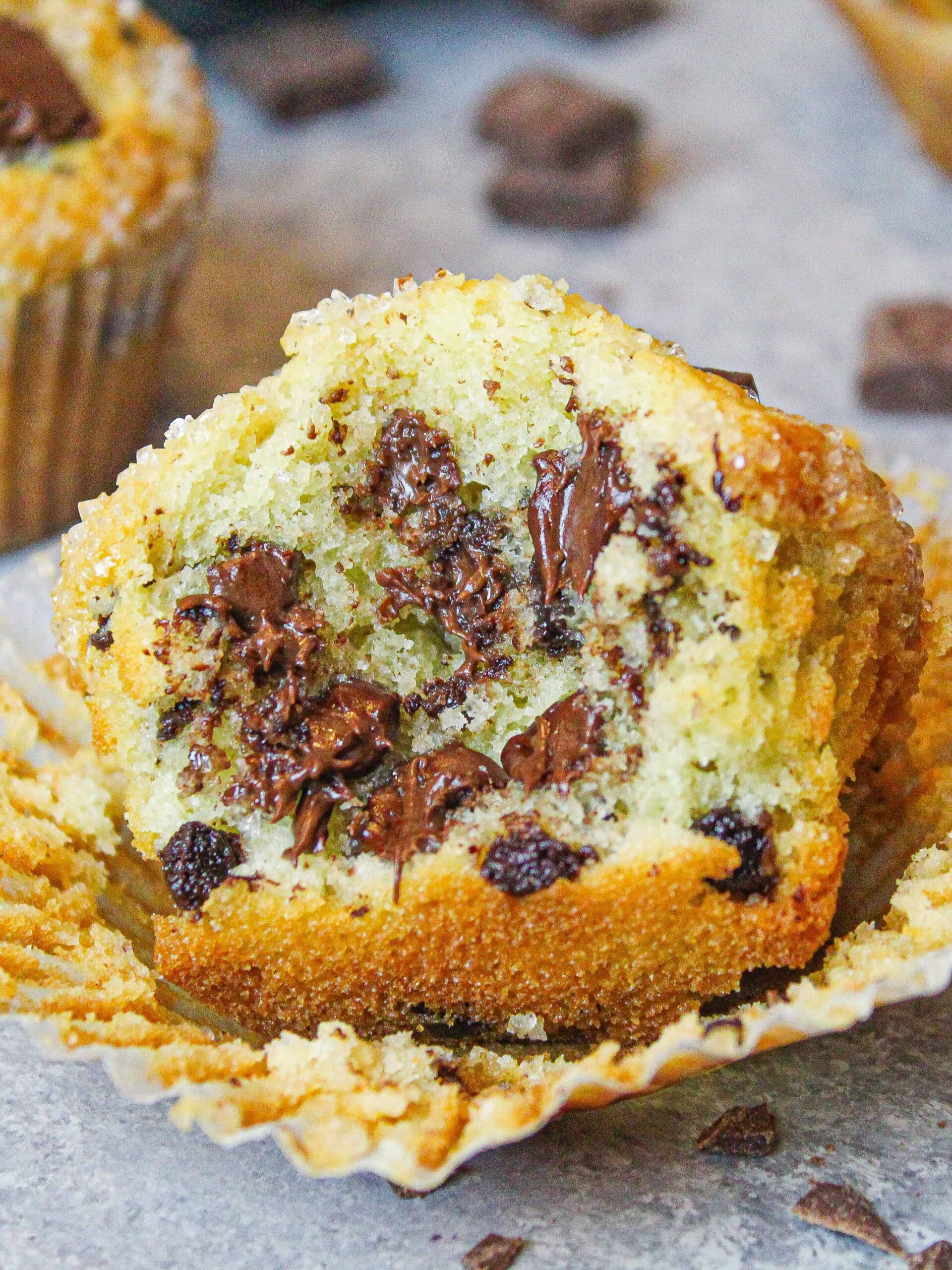 image of a chocolate chip muffin that has been bitten into to show the melting chocolate hidden inside and the fluffy texture