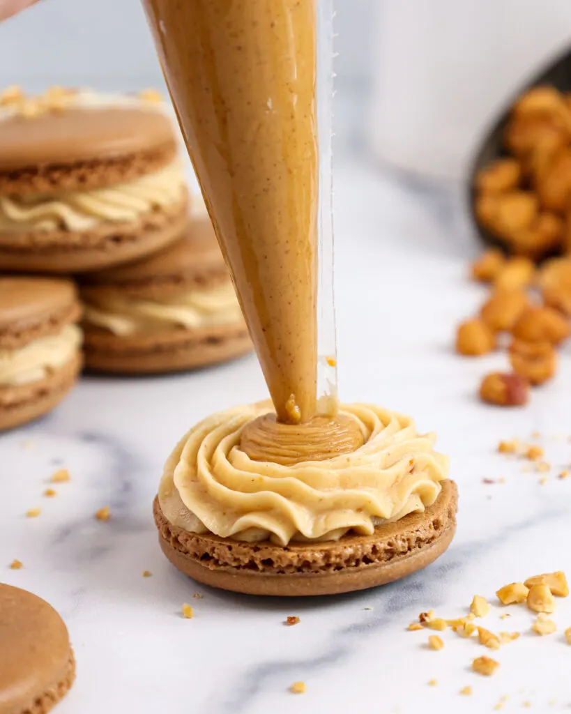 image of peanut butte macarons being filled with honey roasted peanut butter