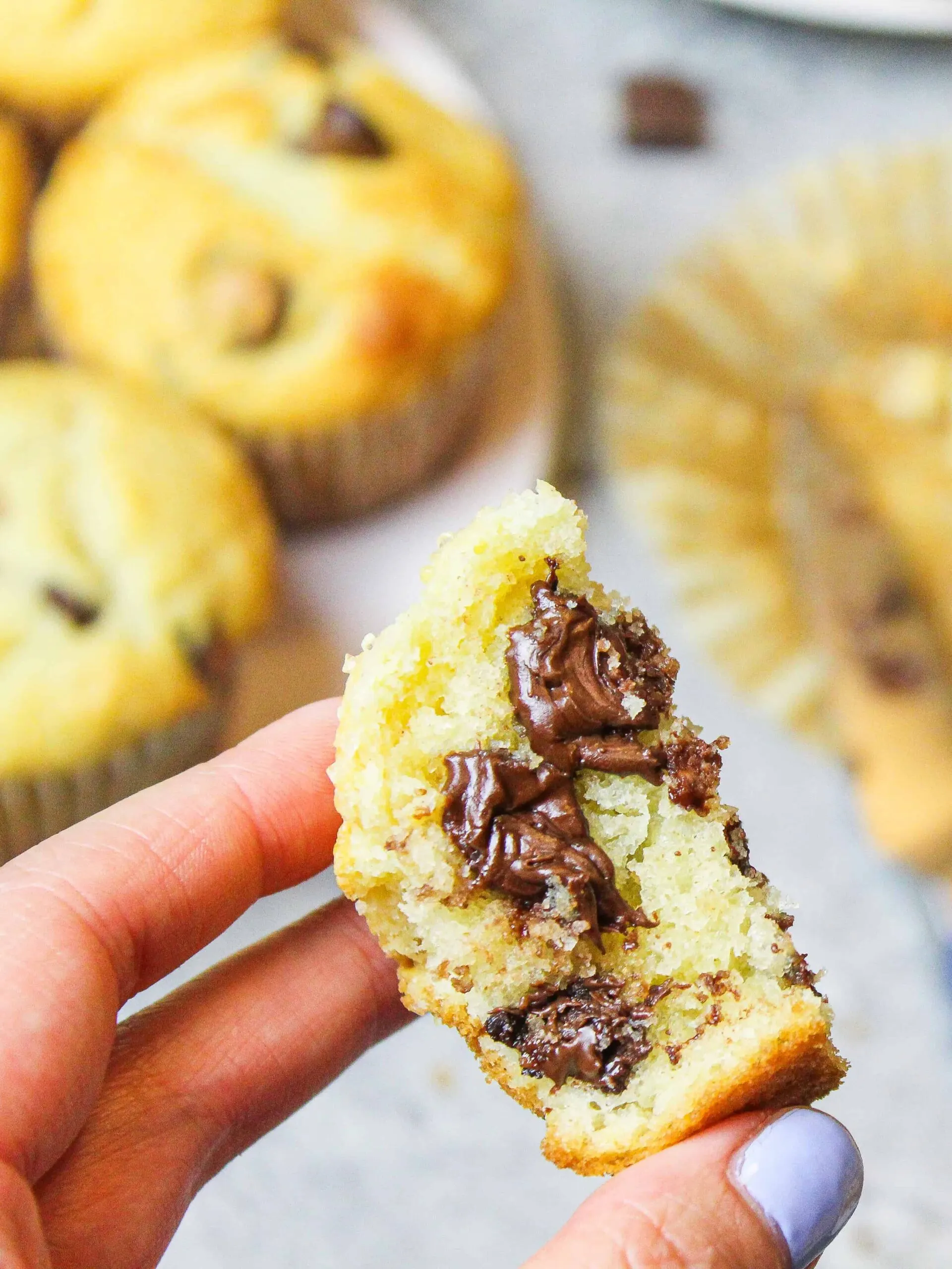 image of piece of chocolate chip muffin with melting chocolate held up before being eaten
