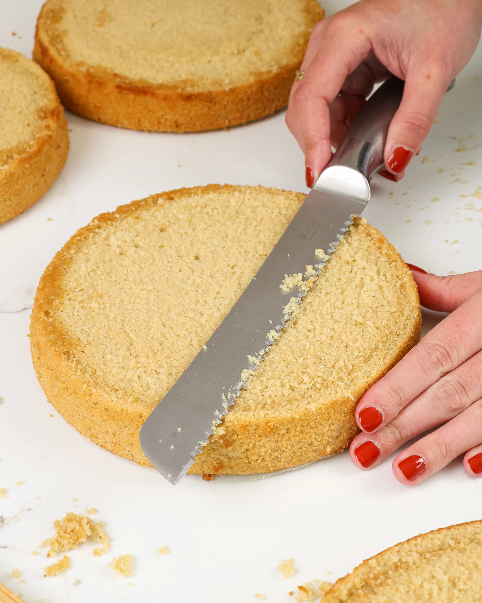 image of a tan cake layer being leveled with a serrated knife