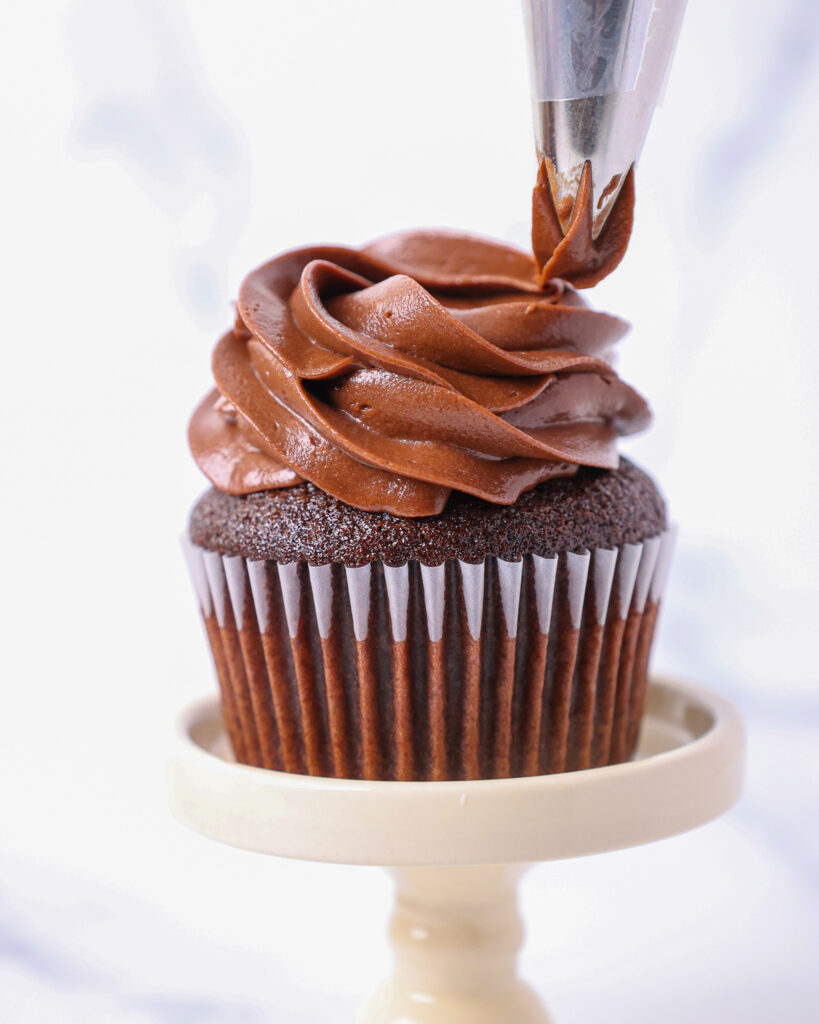 image of chocolate cupcakes being frosted with a wilton 1M frosting tip