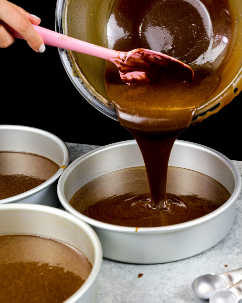 image of dark chocolate batter being poured into 3 8-inch pans