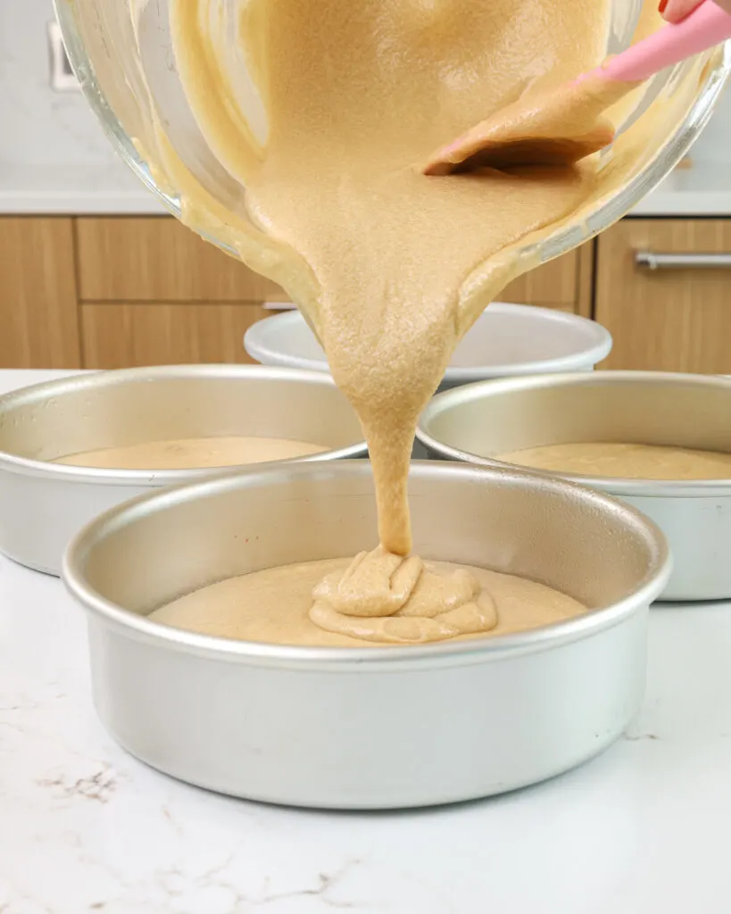 image of sand colored vanilla cake batter being poured into a 7-inch cake pan