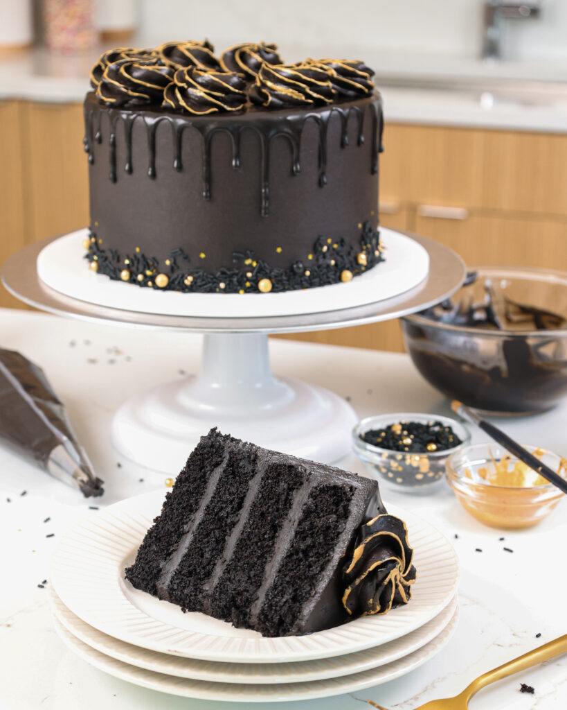 image of a black drip cake that's been decorated with gold sprinkles and edible gold paint